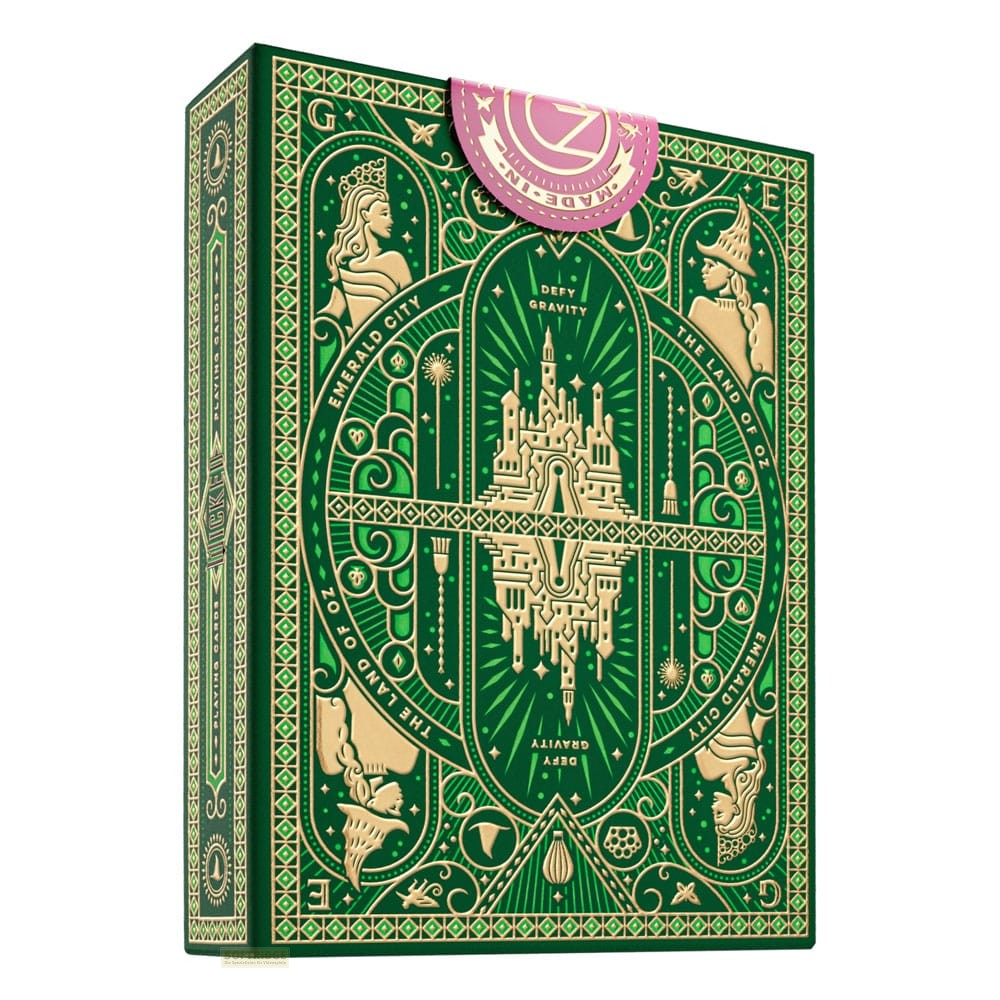 Une boîte de cartes à jouer verte ornée de motifs dorés d'Oz, d'un château et de personnages sur fond blanc.