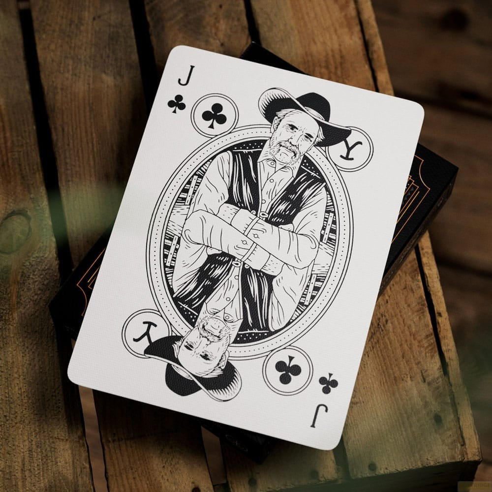 Une carte à jouer, Valet de Trèfle, montre l'illustration d'un cowboy en noir et blanc, posée sur du bois.