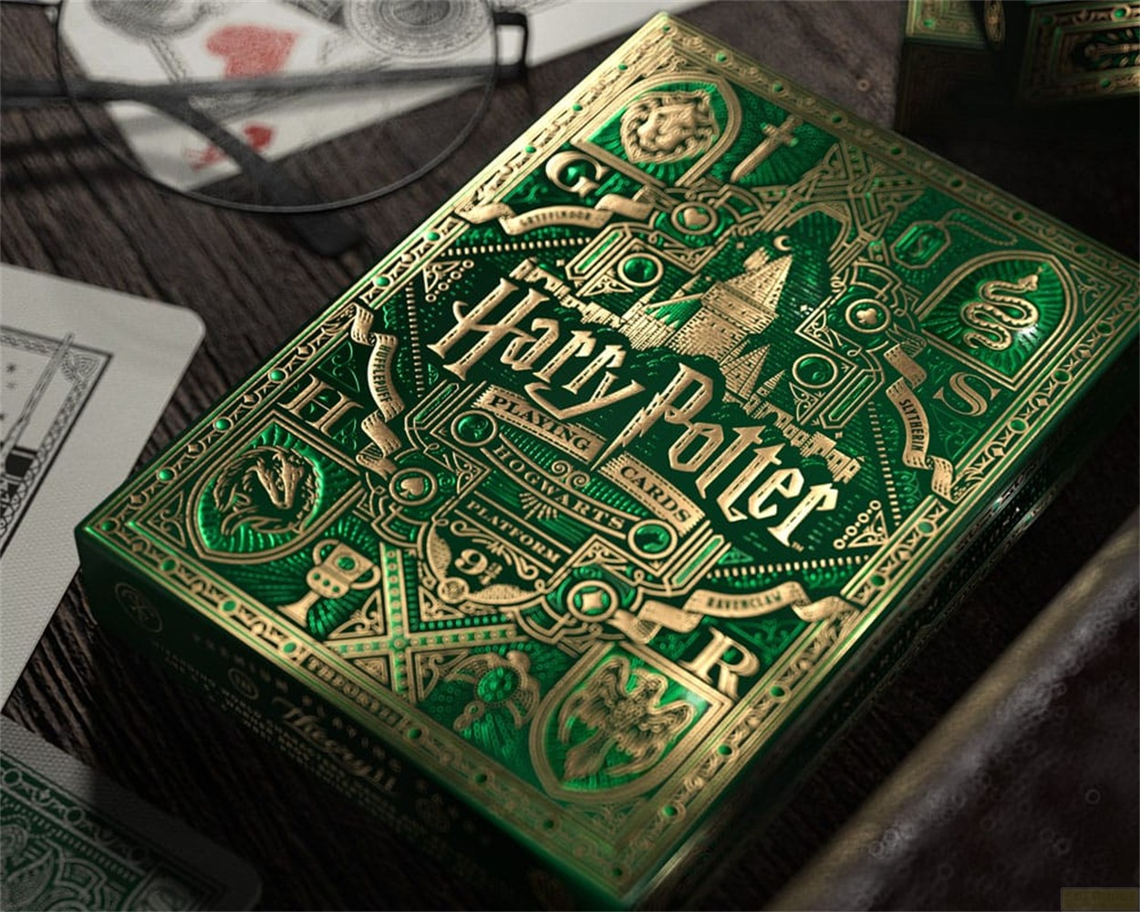 Une boîte de cartes à jouer Harry Potter verte avec des détails dorés en relief sur une table.
