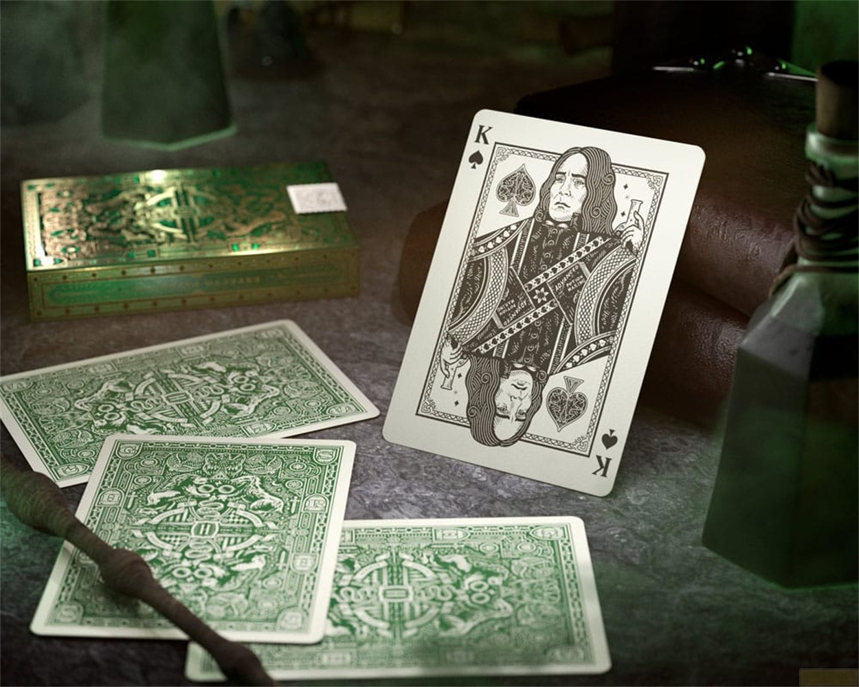 Une carte à jouer représentant le professeur Snape se trouve parmi des cartes vertes, une boîte et des bouteilles.
