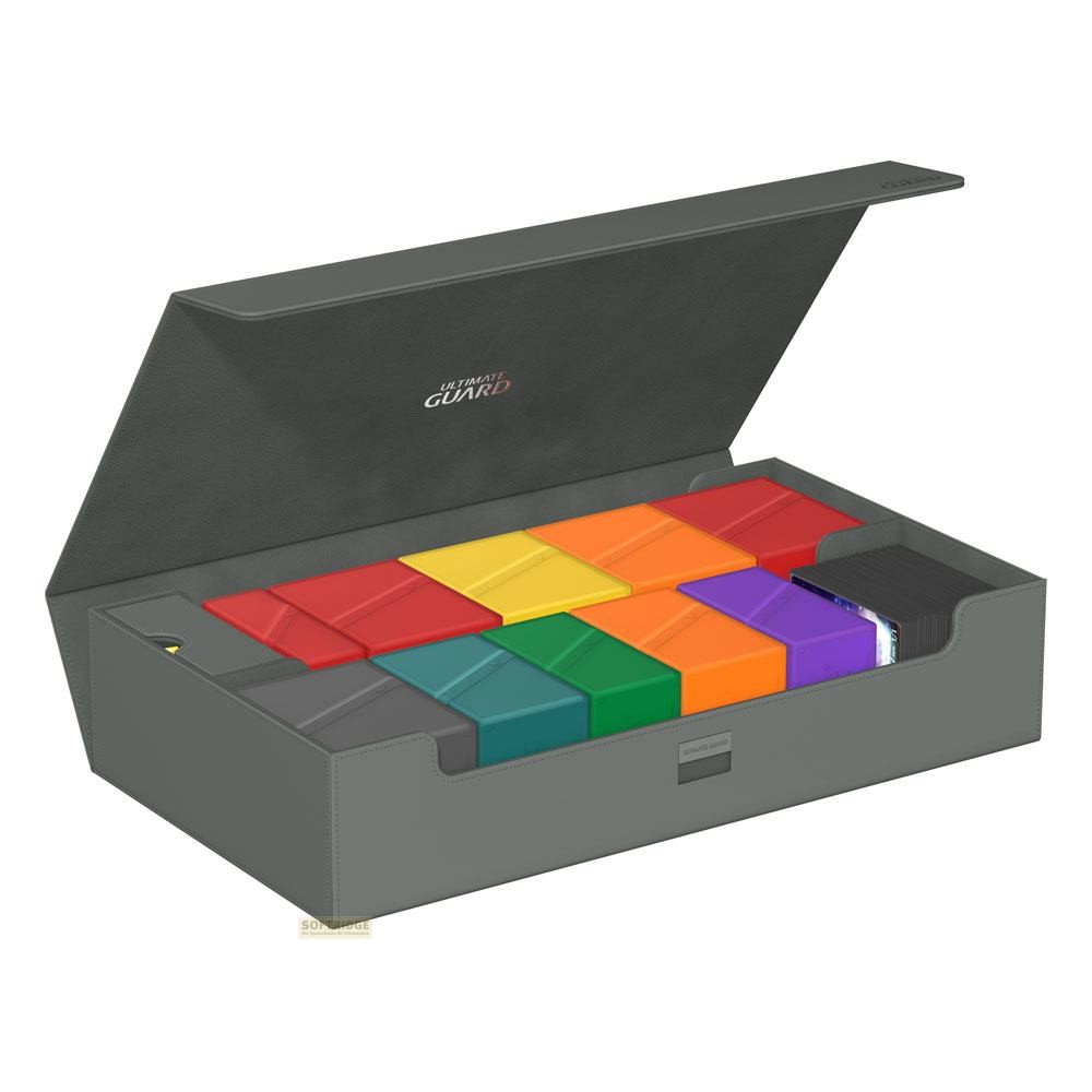 Une boîte ouverte grise contient de petites boîtes colorées organisées et un jeu de cartes.