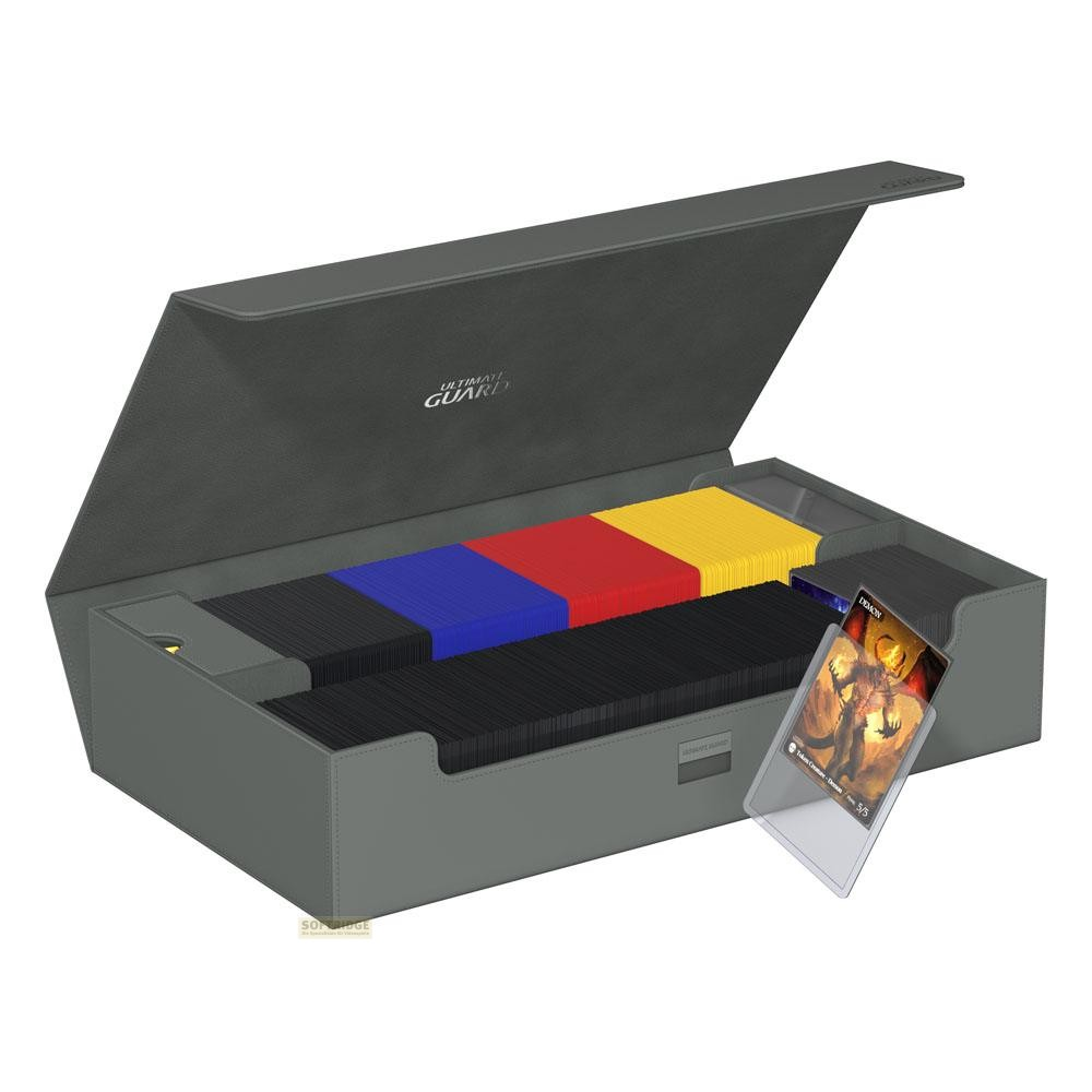 Une boîte de rangement grise ouverte contient des cartes à collectionner bien rangées, une carte sur le côté.