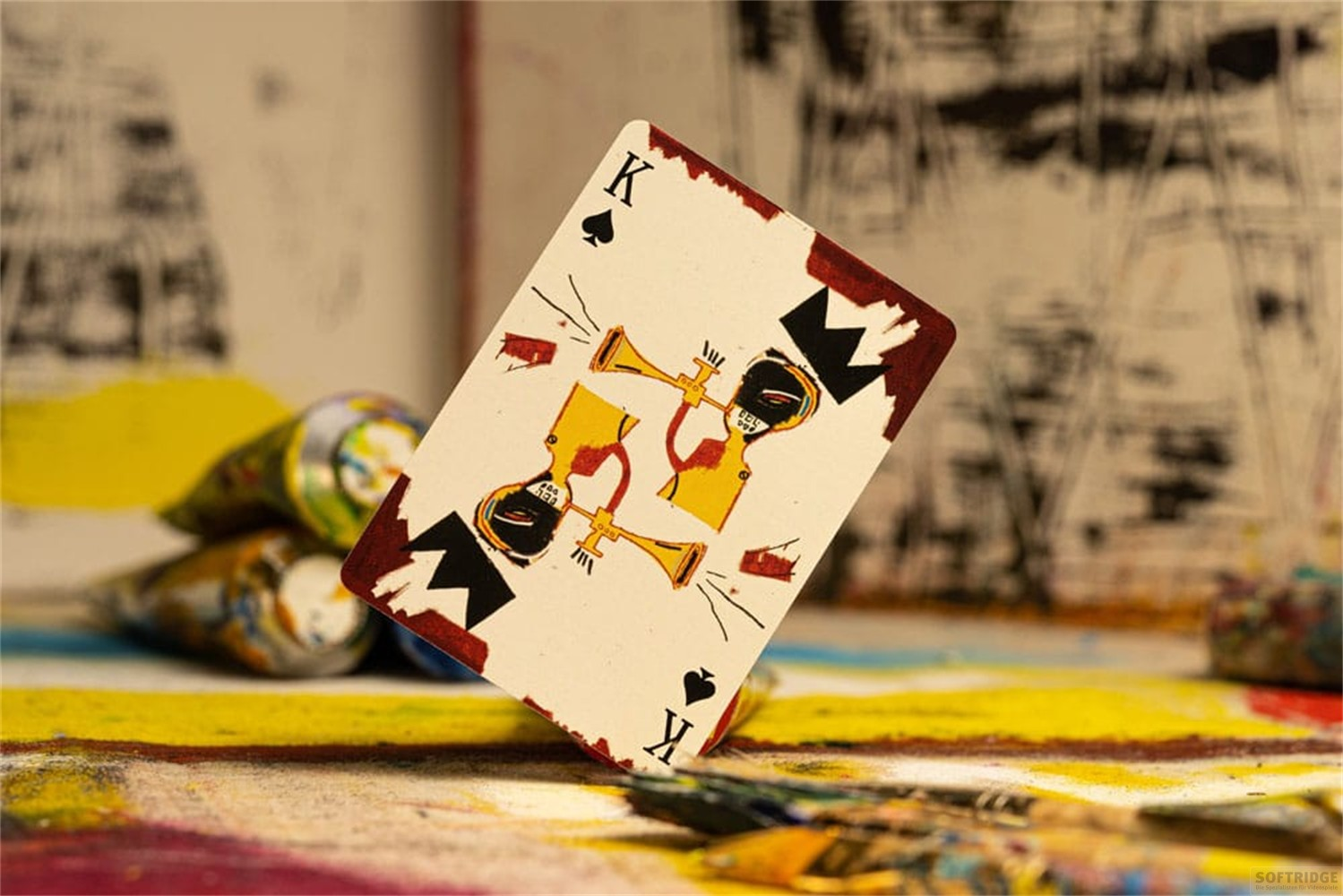 Une carte à jouer avec le Roi de Pique et un art unique se trouve sur une table de peinture.