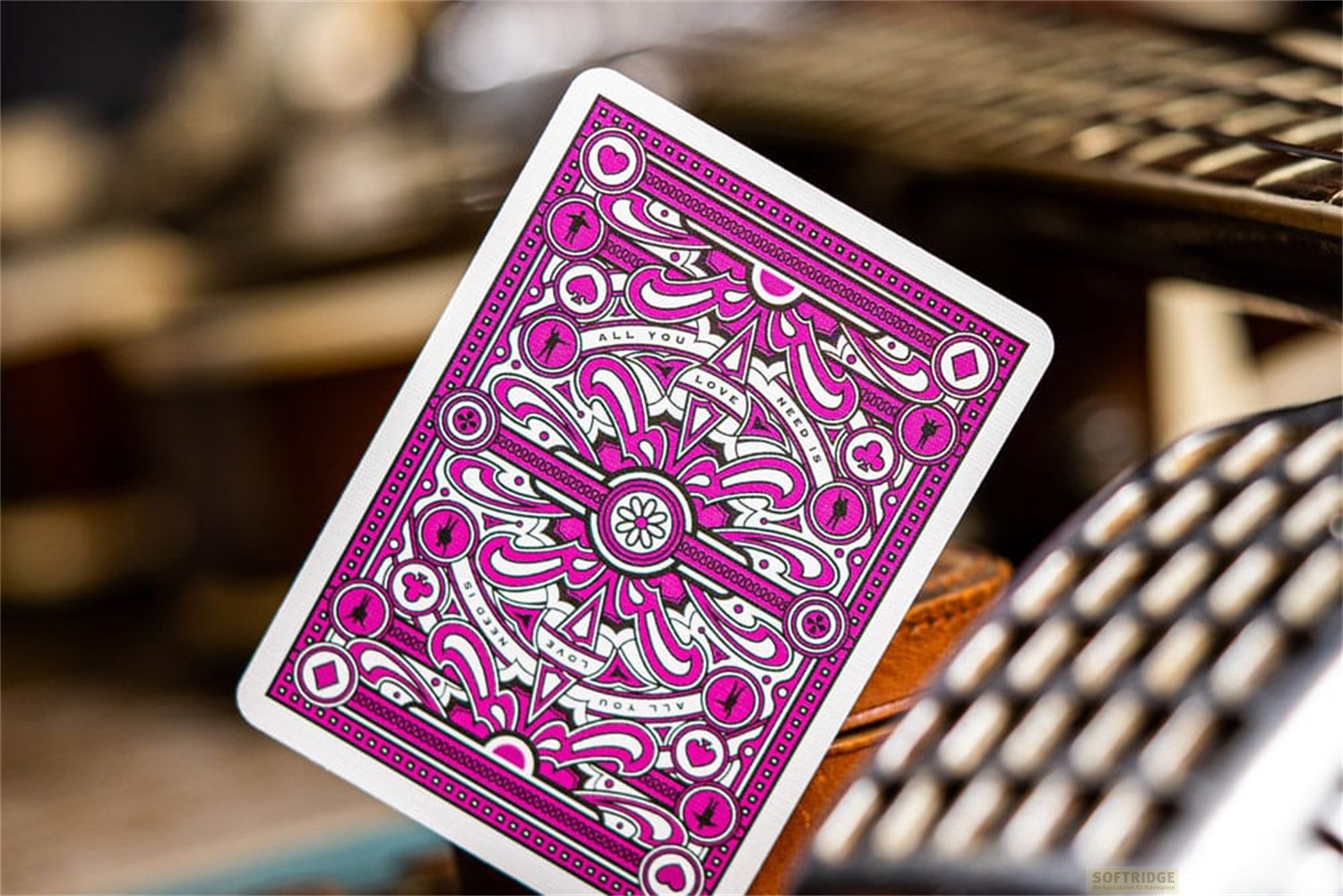 Une carte à jouer blanche et rose avec des motifs complexes sur un fond flou.