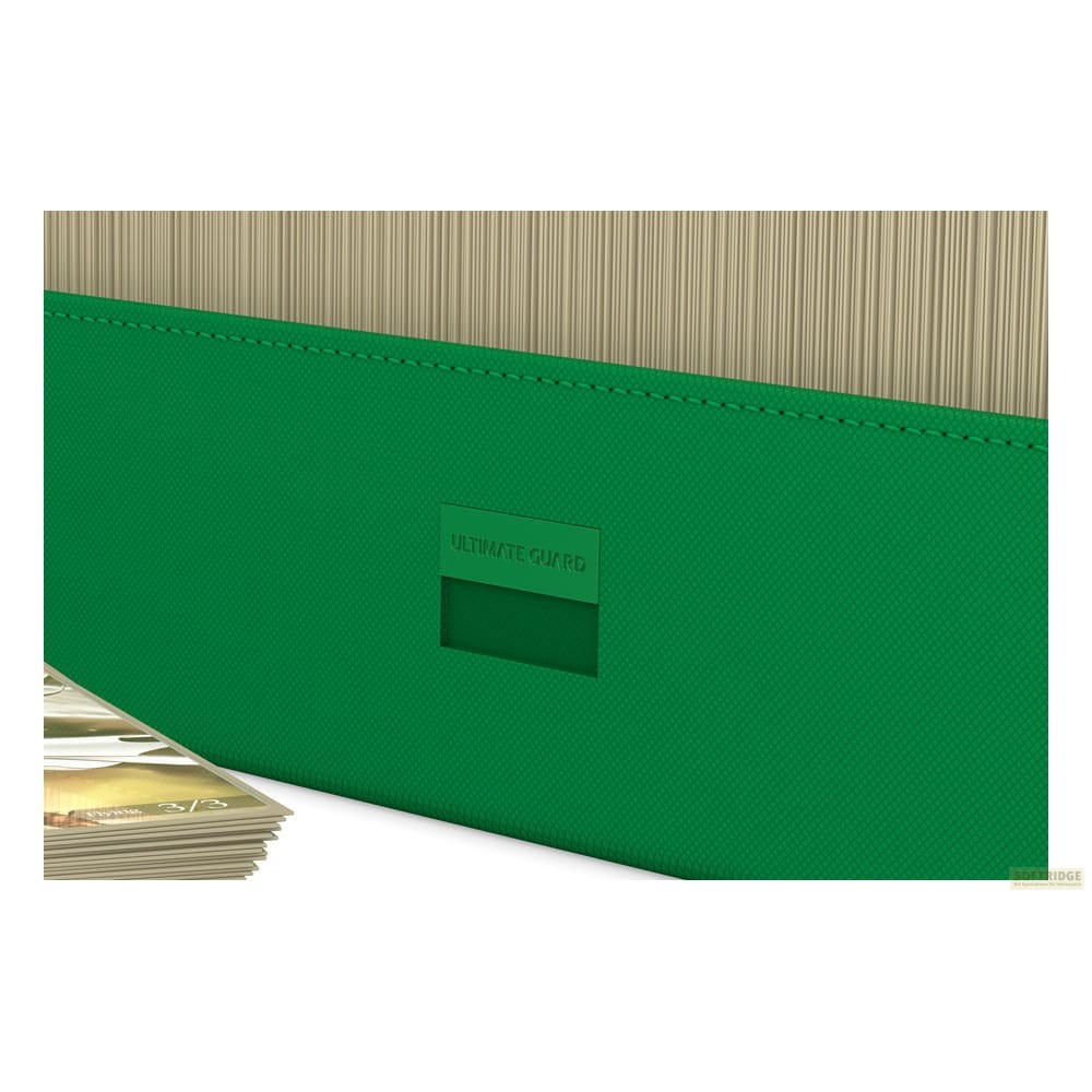 Une boîte de cartes verte Ultimate Guard avec un tas de cartes sur fond blanc.