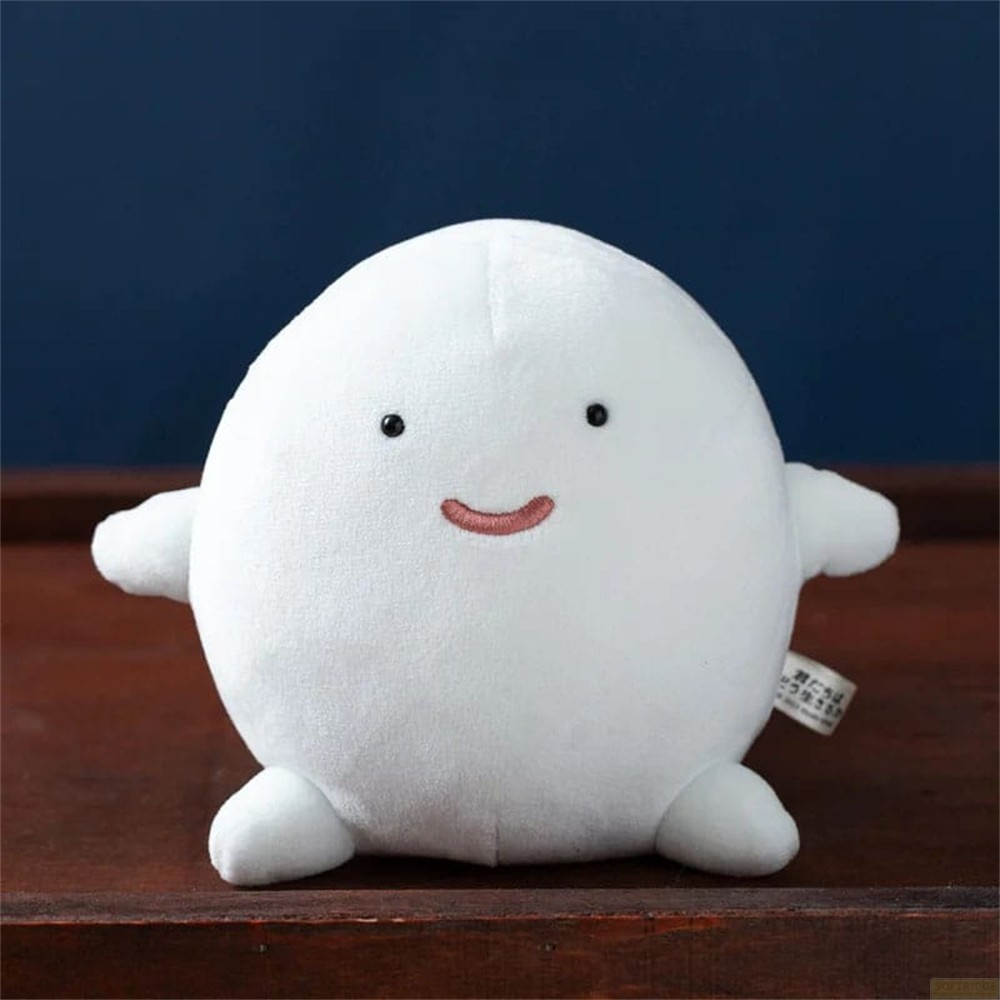 Un fantasma de peluche blanco y redondo con ojos negros y una sonrisa rosa sobre una tabla de madera.