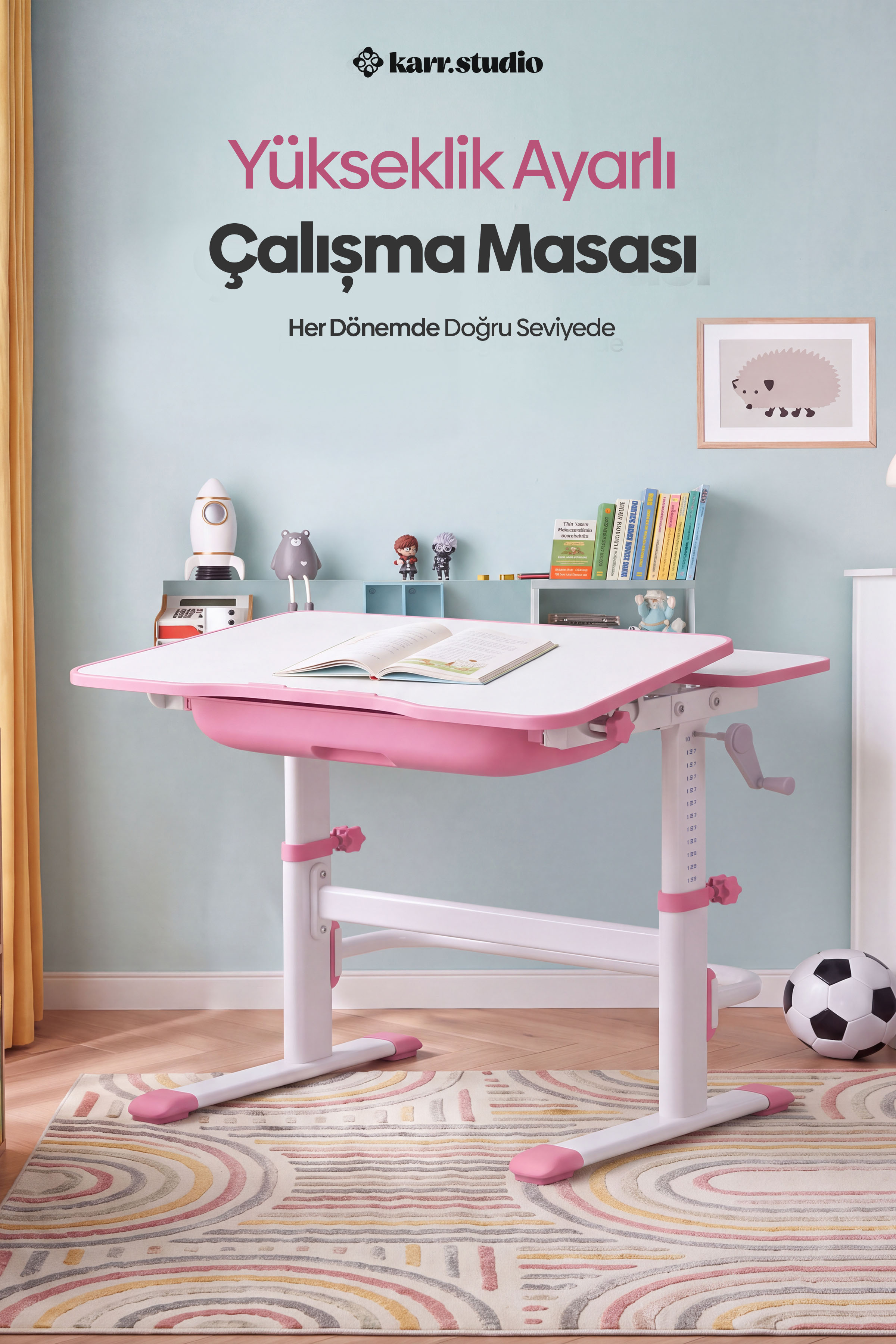 Açık kitap bulunan pembe beyaz çocuk çalışma masası, açık mavi duvar önünde desenli halı üstünde duruyor.