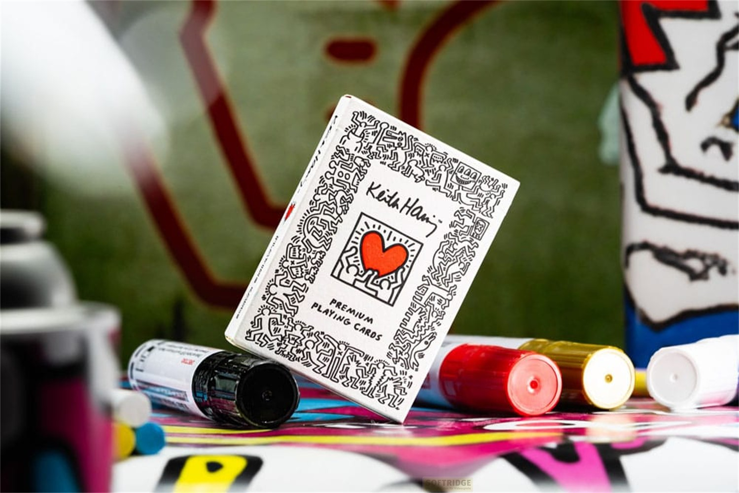 Un jeu de cartes design Keith Haring posé parmi des marqueurs colorés.