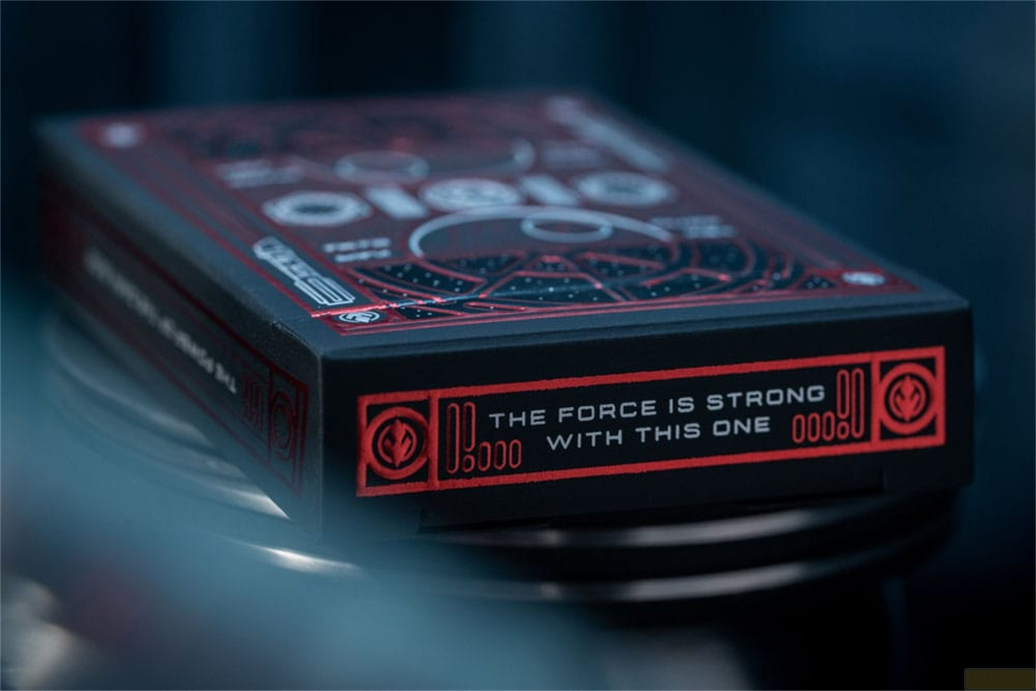 Une boîte de cartes à jouer noire avec un design rouge Star Wars et le texte The Force is Strong With This One.