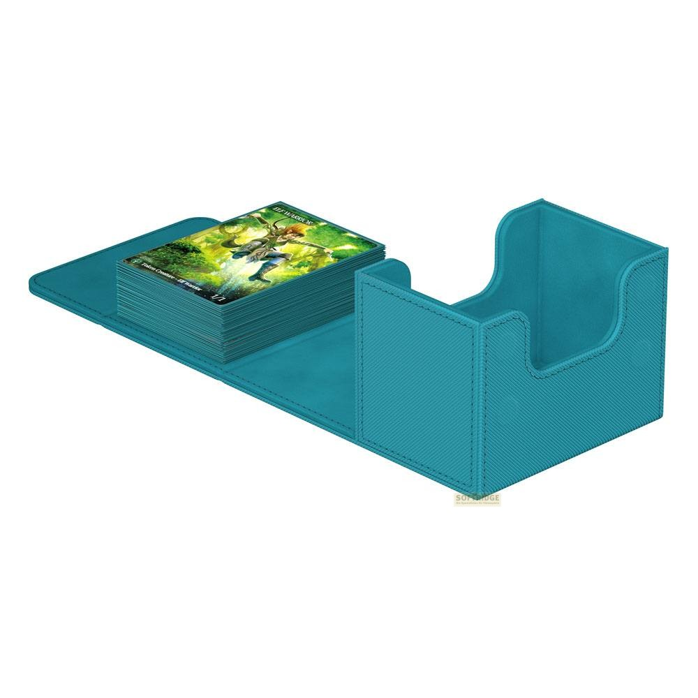 Boîte de deck sarcelle ouverte avec une pile de cartes à collectionner à côté sur une surface assortie.