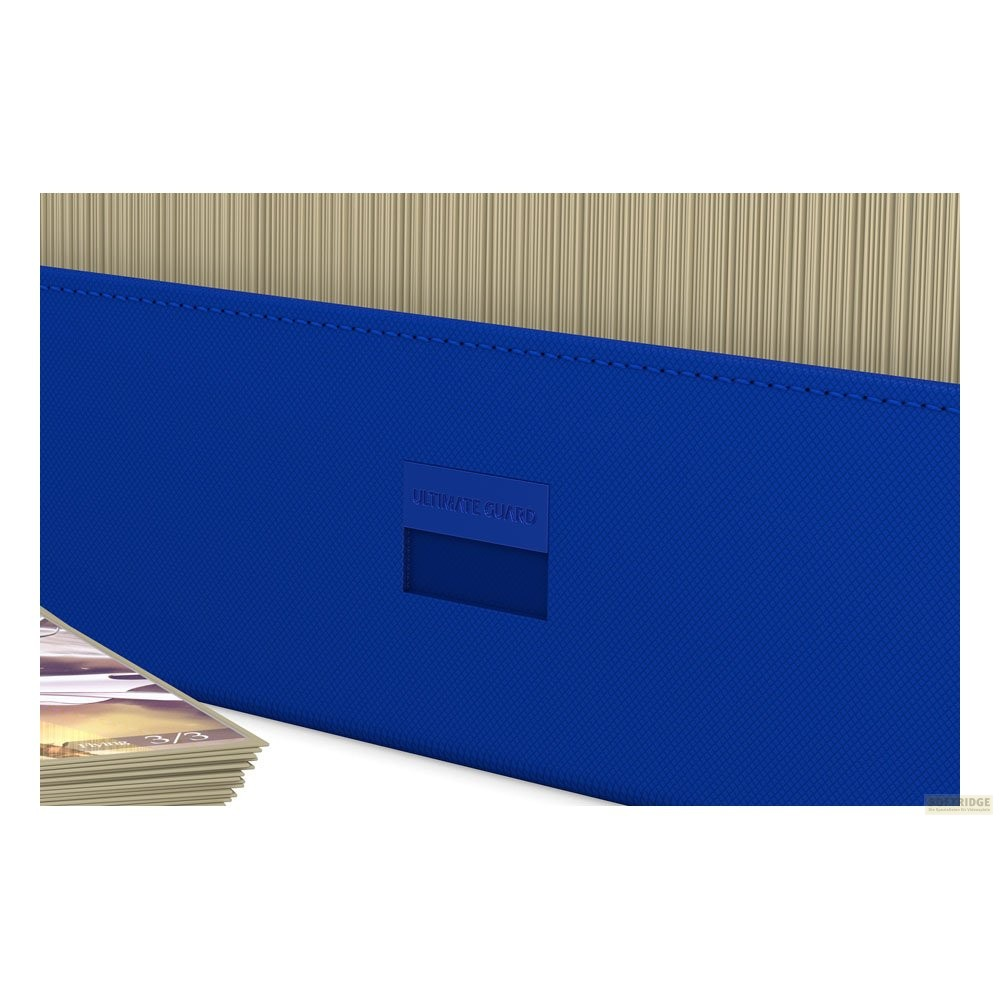Boîte de cartes Ultimate Guard bleue avec une pile de cartes à collectionner visible au premier plan.