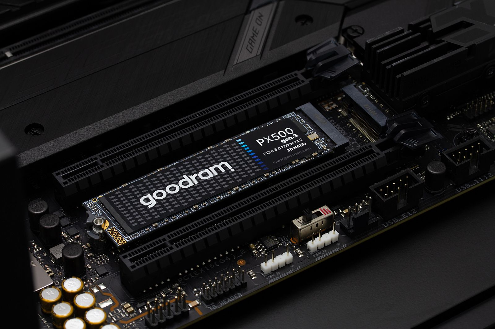 Un SSD M.2 NVMe Goodram PX500 está conectado a la ranura M.2 de una placa base de computadora oscura.