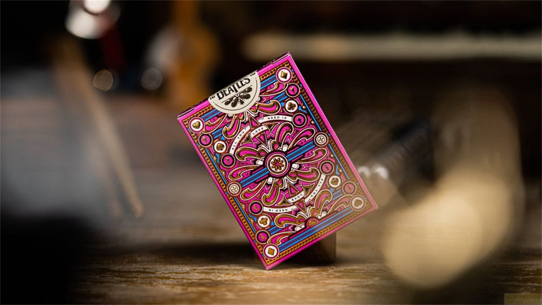 Un jeu de cartes rose avec des motifs colorés et ornés posé sur une table en bois.