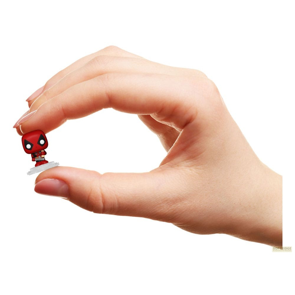 Una mano sostiene suavemente una pequeña figura de Deadpool entre el pulgar y el índice sobre fondo blanco.
