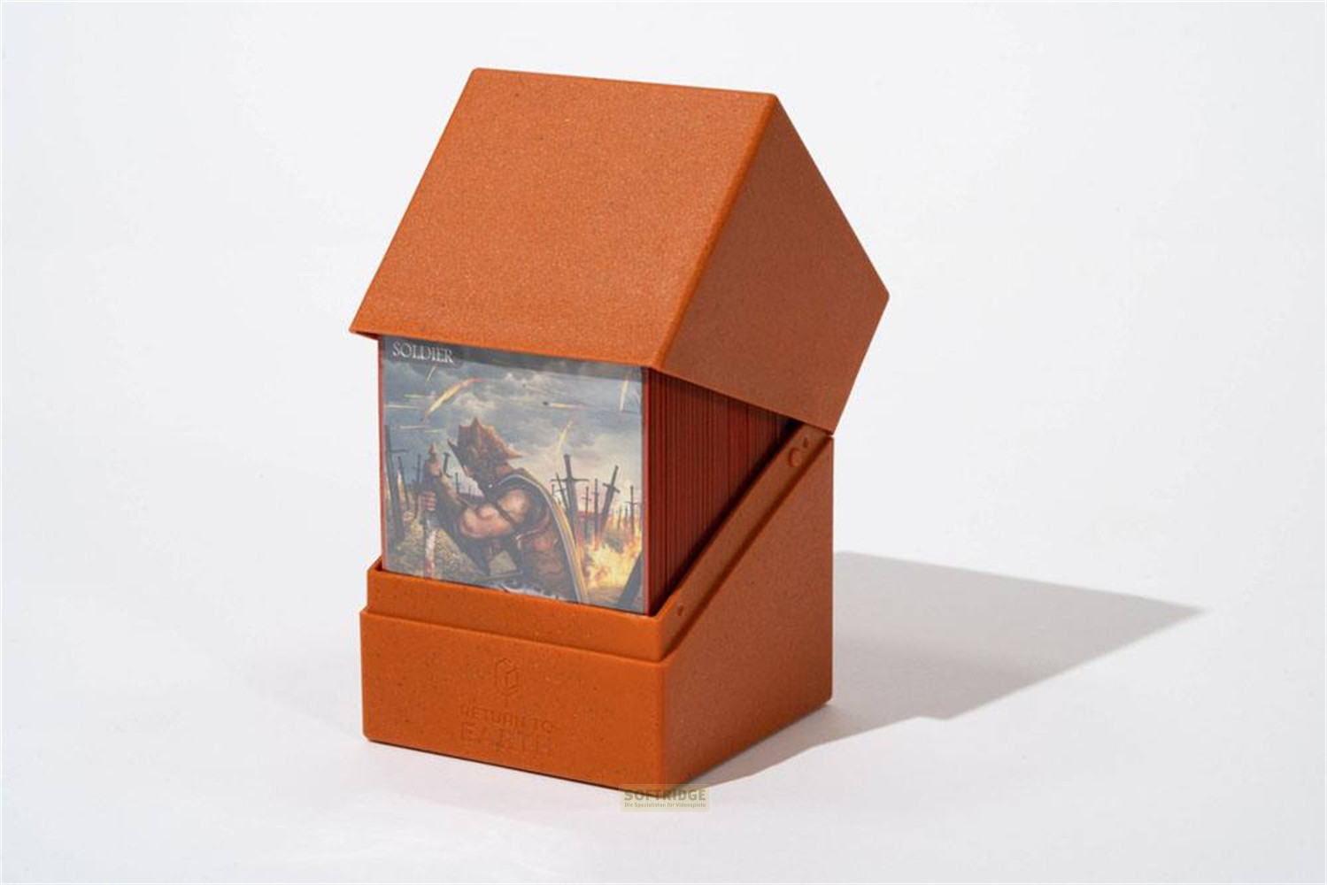 Une boîte de jeu orange ouverte avec une carte de soldat fantastique visible à l'intérieur, sur fond blanc.