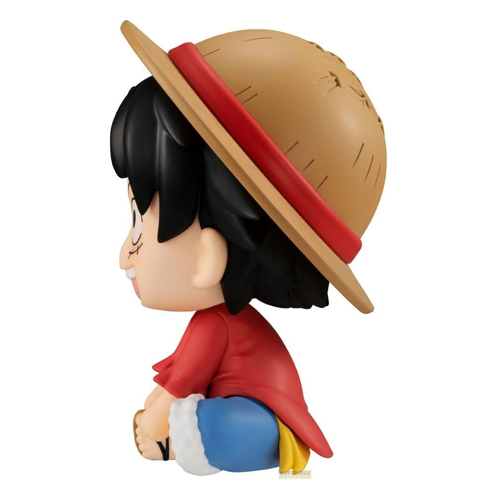 Una figura de anime sentada con cabello negro, sombrero de paja, camisa roja y pantalones cortos azules.