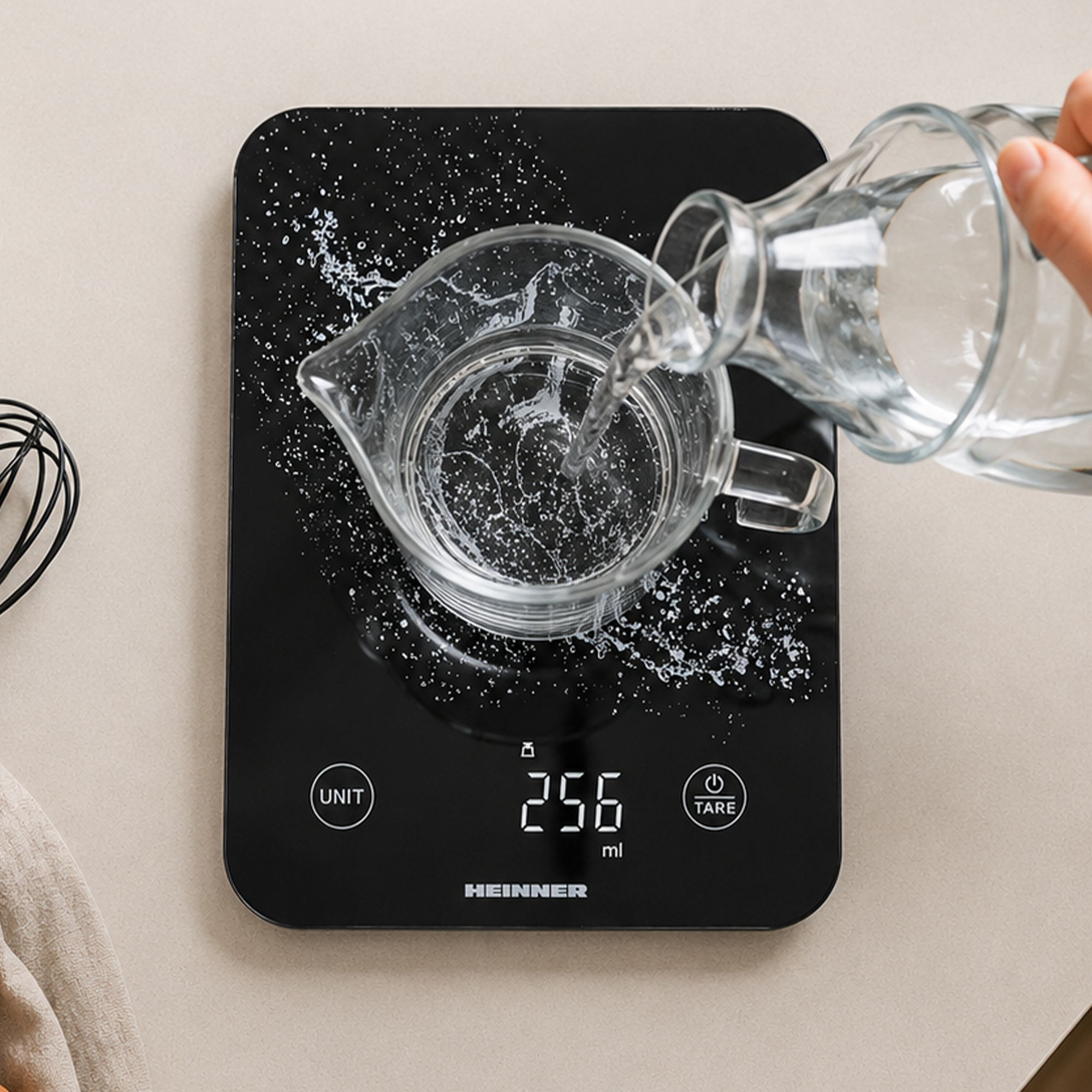 Wasser wird aus einer Kanne in eine Tasse auf einer digitalen Küchenwaage gegossen.