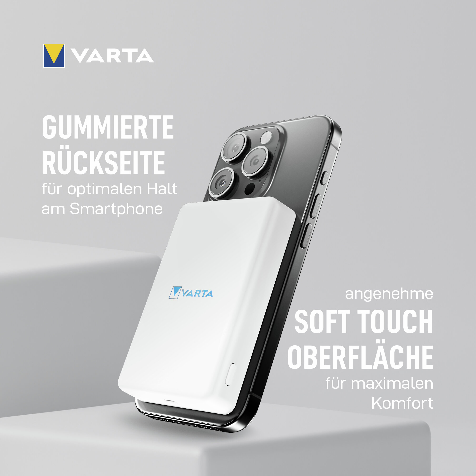 Un banco de energía Varta blanco está unido a la parte posterior de un teléfono inteligente gris, sobre un fondo gris.