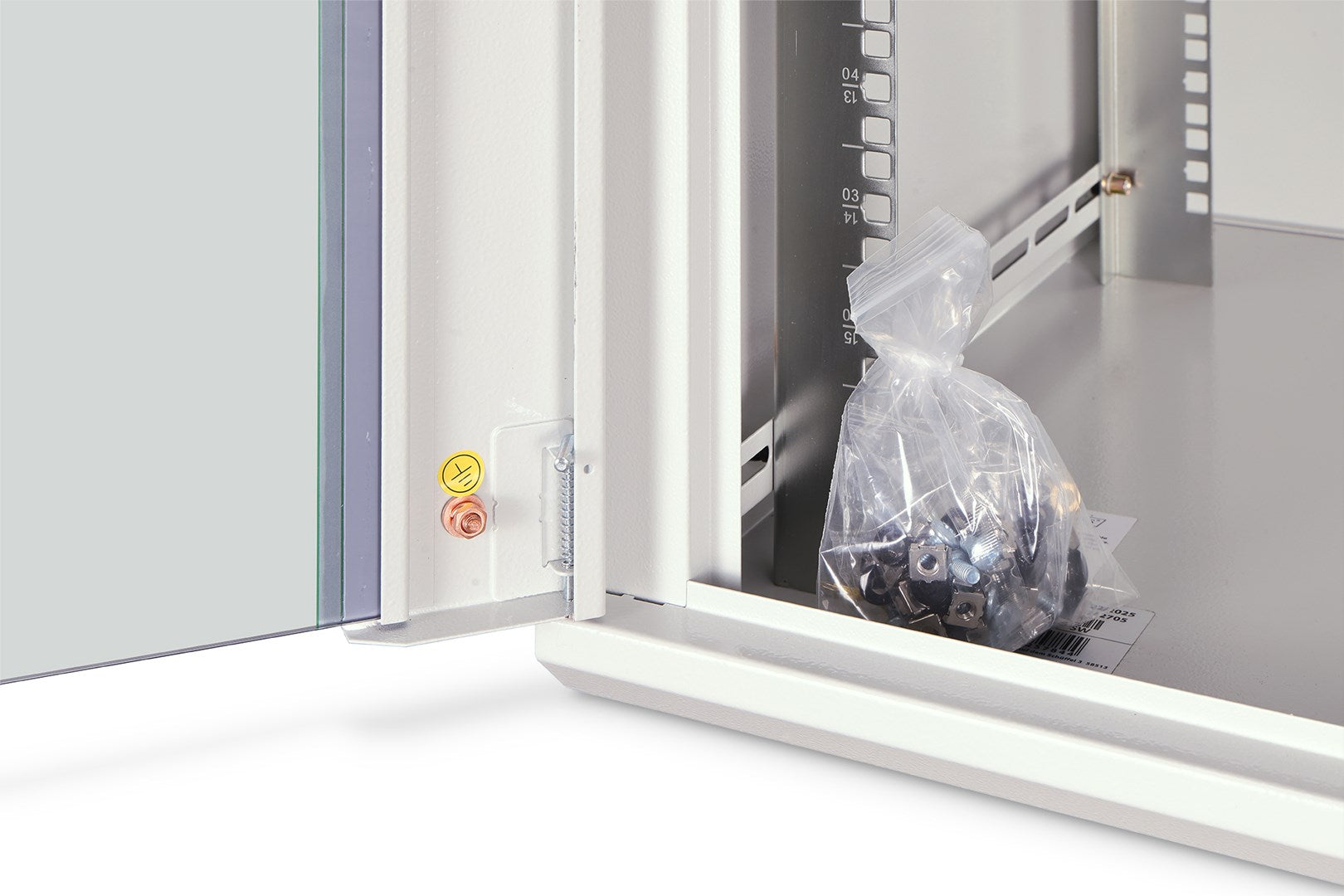 Ein Plastikbeutel mit Metallschrauben und Muttern liegt in einem offenen weißen Serverschrank.