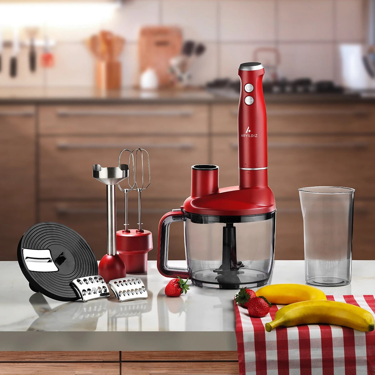 Mutfak tezgahında aparatları, çilekler ve muzlarla birlikte kırmızı el blender seti.