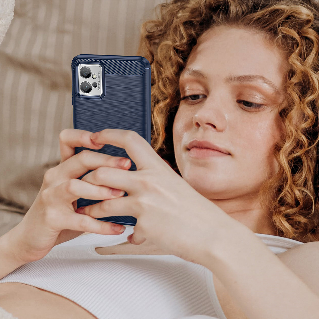 Una donna riccia tiene in mano uno smartphone blu con cover testurizzata.