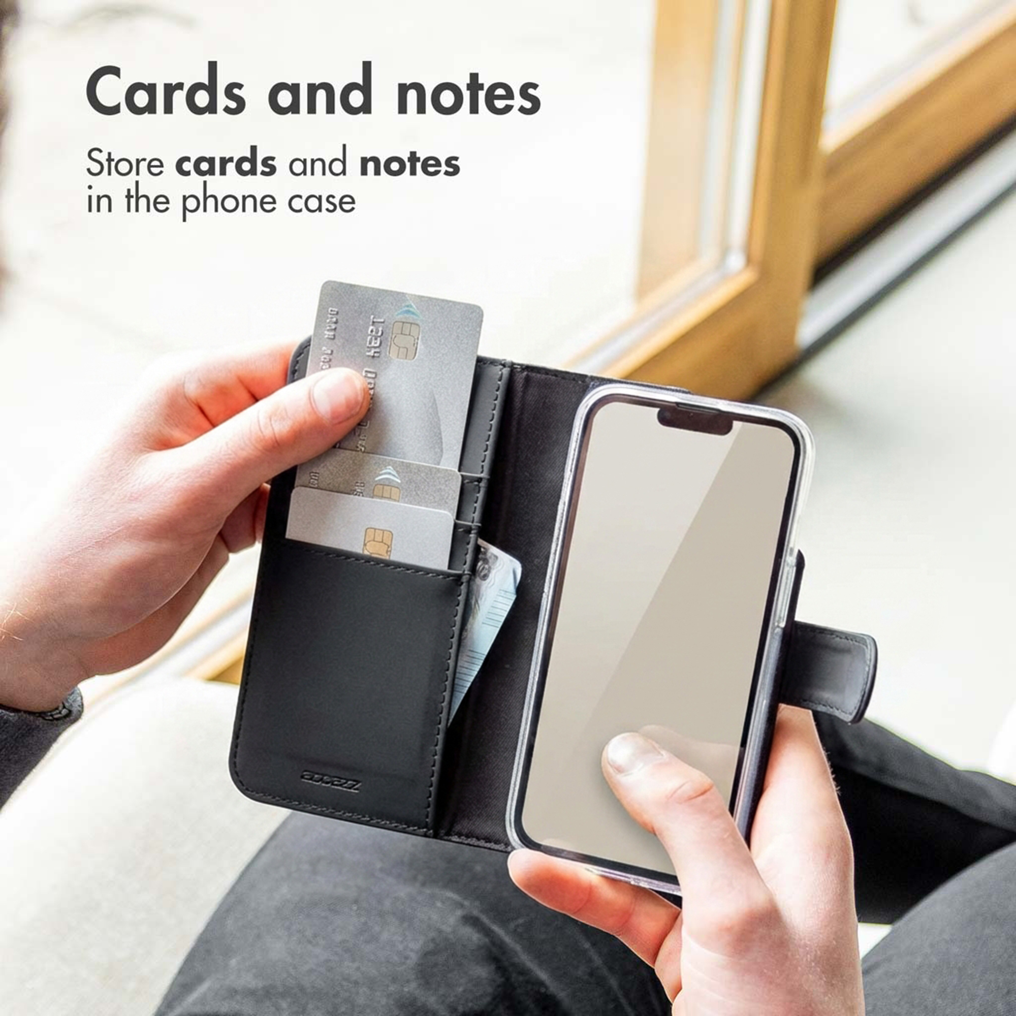 Une personne tient un étui portefeuille de téléphone noir ouvert avec des cartes et un smartphone.