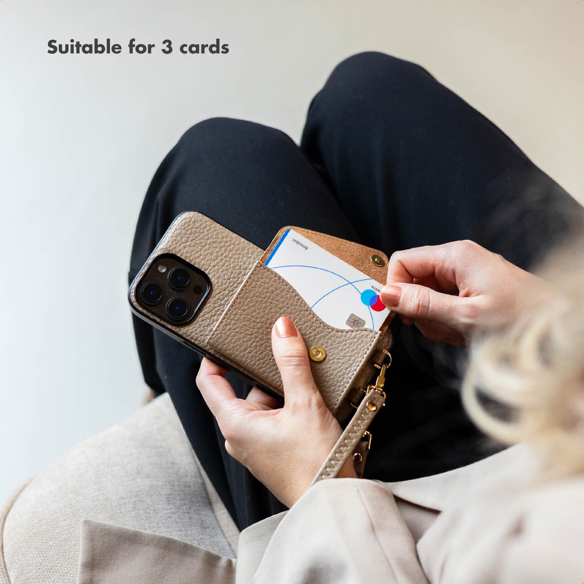 Una persona tiene una custodia in pelle beige con porta carte per tre carte, testo: Adatto per 3 carte.