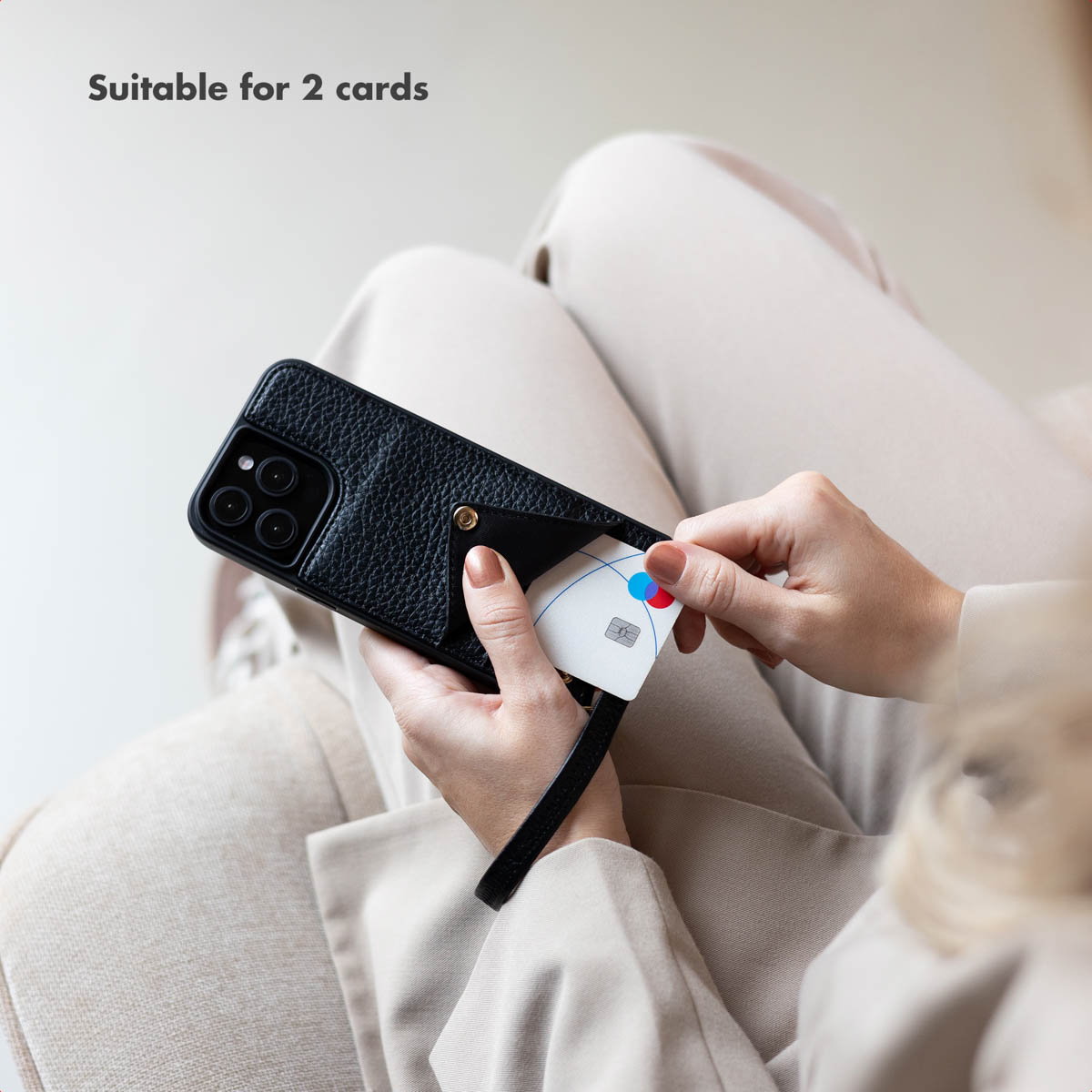 Person in heller Kleidung hält ein schwarzes Leder-Smartphone-Case mit integriertem Kartenfach und einer Karte.