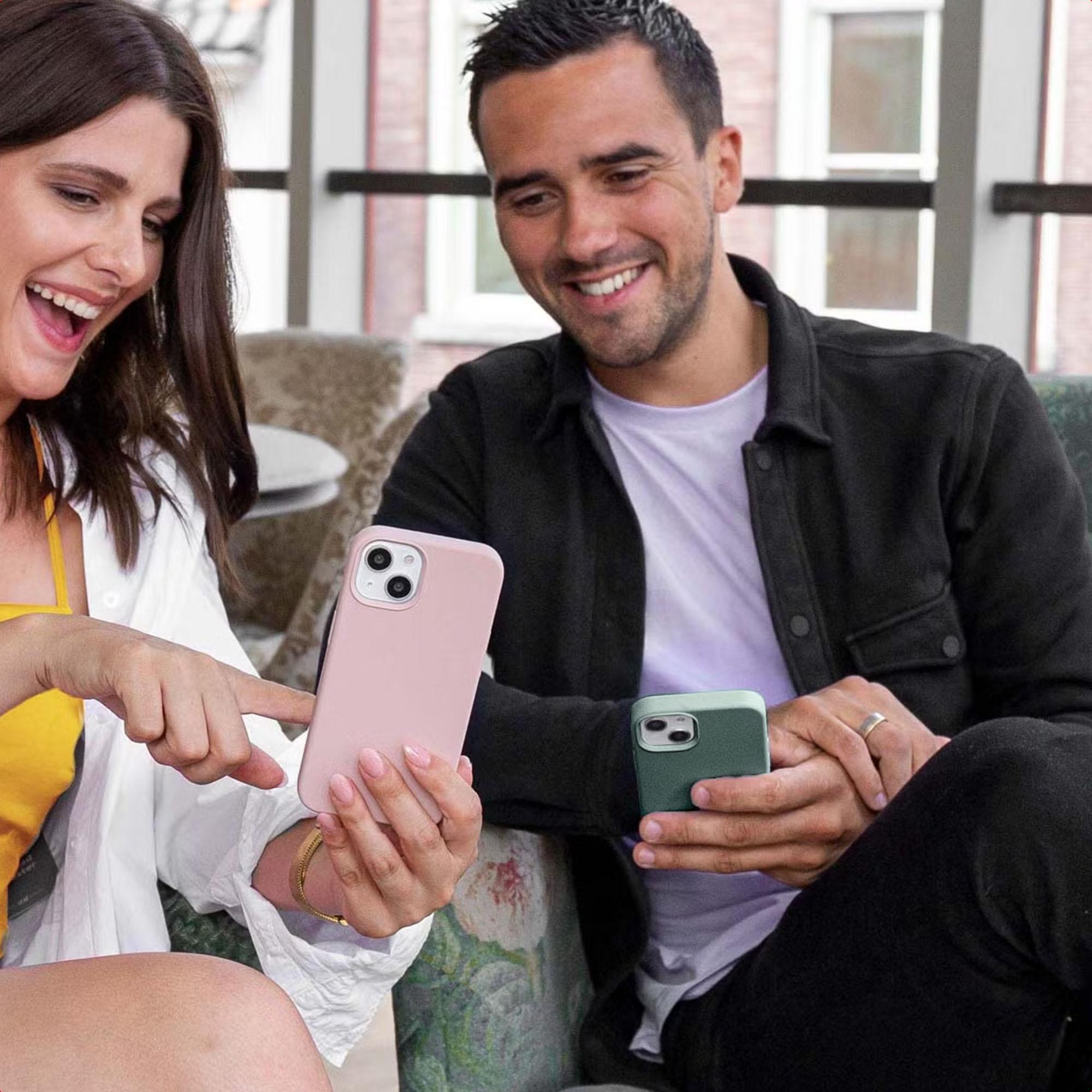 Uśmiechnięta kobieta wskazuje różowy smartfon, a stojący obok mężczyzna trzyma zielony.