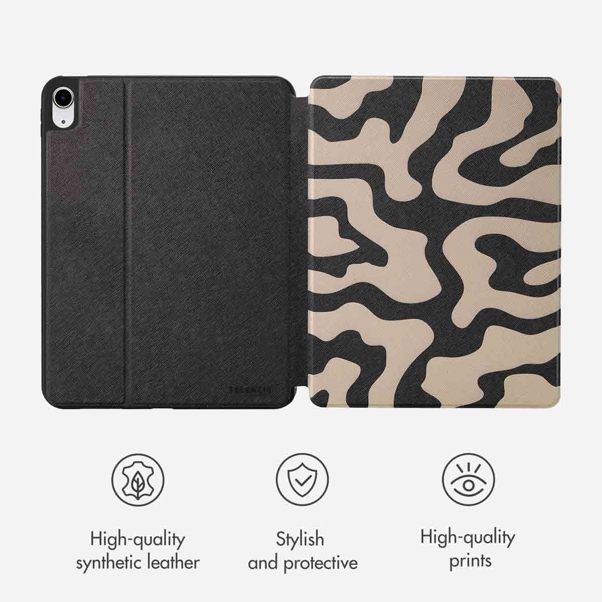Een leren tabletcover met een zwarte voorkant en beige-zwart geprinte achterkant op een grijze achtergrond.