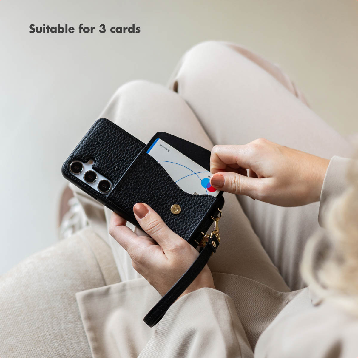 Personne tenant un étui de téléphone en cuir noir avec porte-cartes et cartes insérées.
