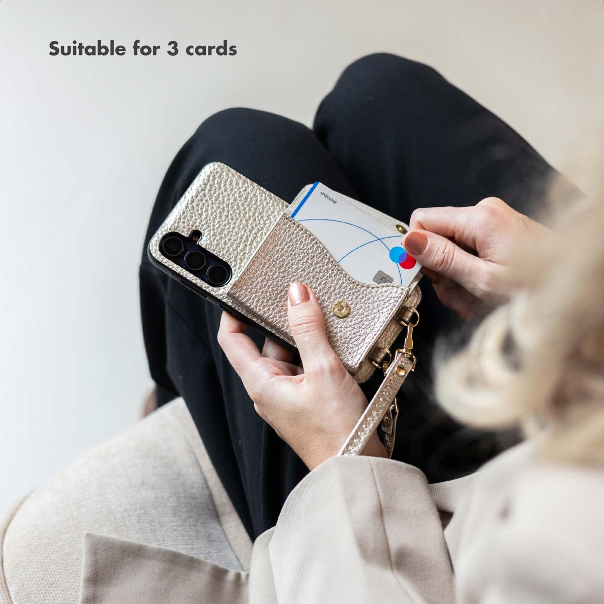 Personne tenant un étui de smartphone doré brillant avec un porte-cartes intégré.