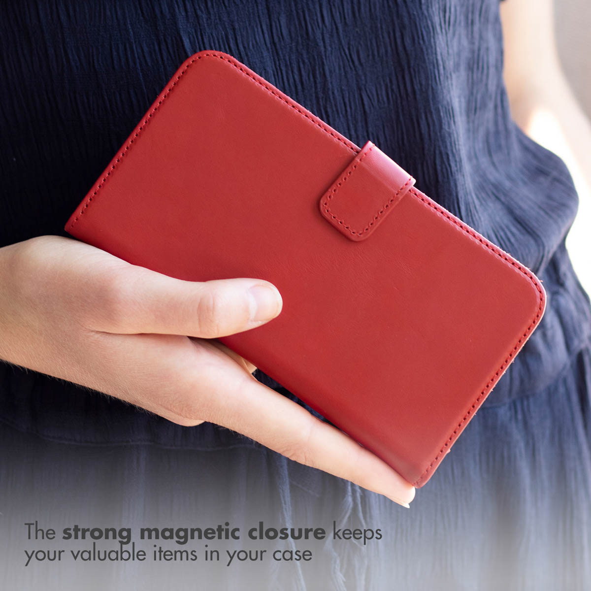 Una persona tiene in mano una custodia per telefono in pelle rossa con chiusura magnetica.