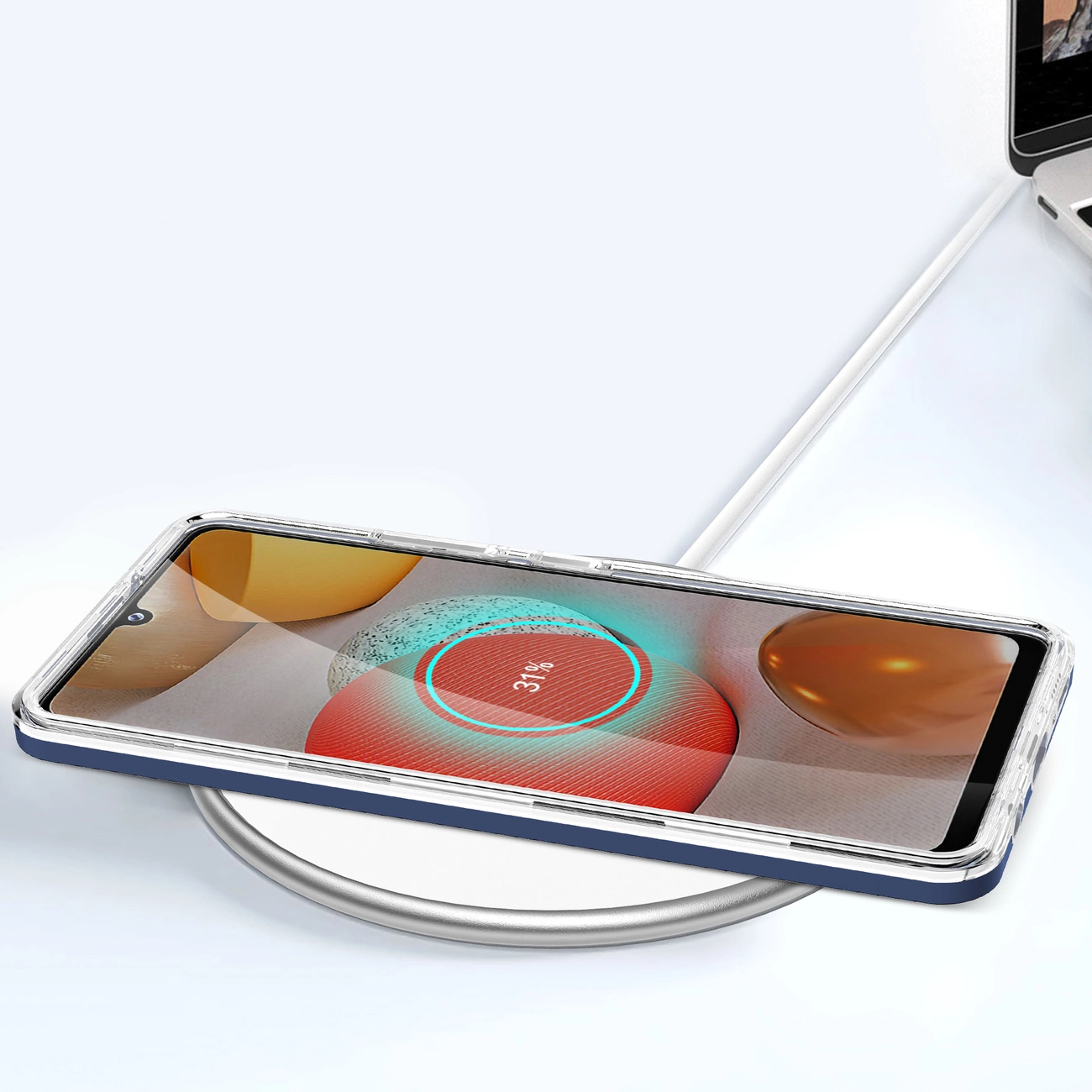 Uno smartphone si ricarica in modalità wireless su una base bianca, collegato a un computer portatile.