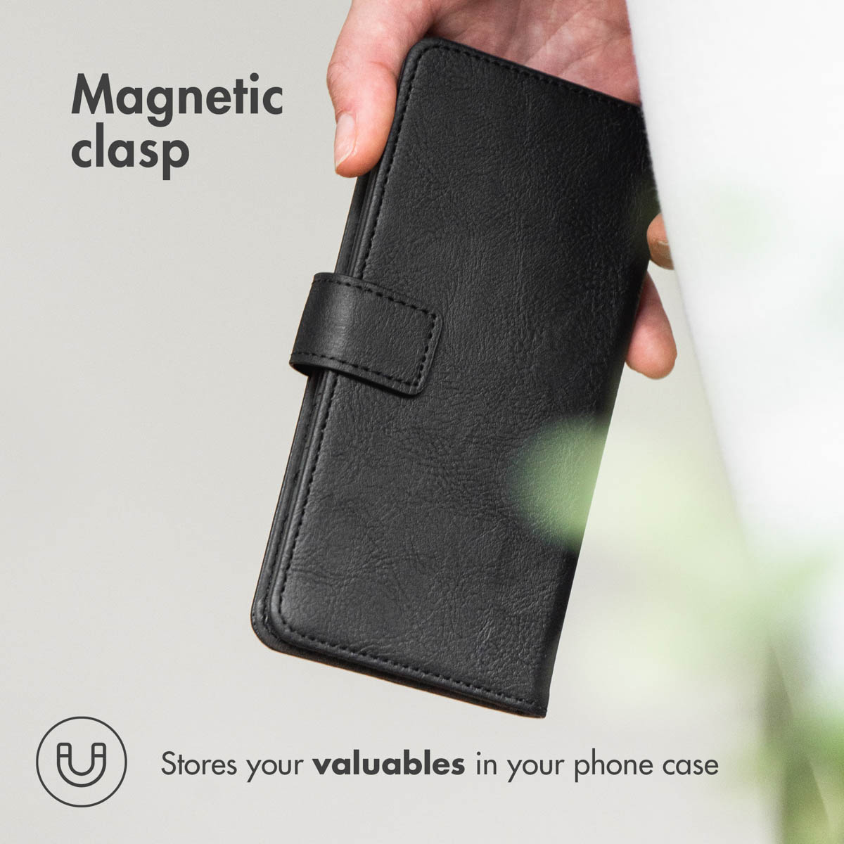 Una mano sostiene una custodia per telefono in pelle nera con chiusura magnetica.