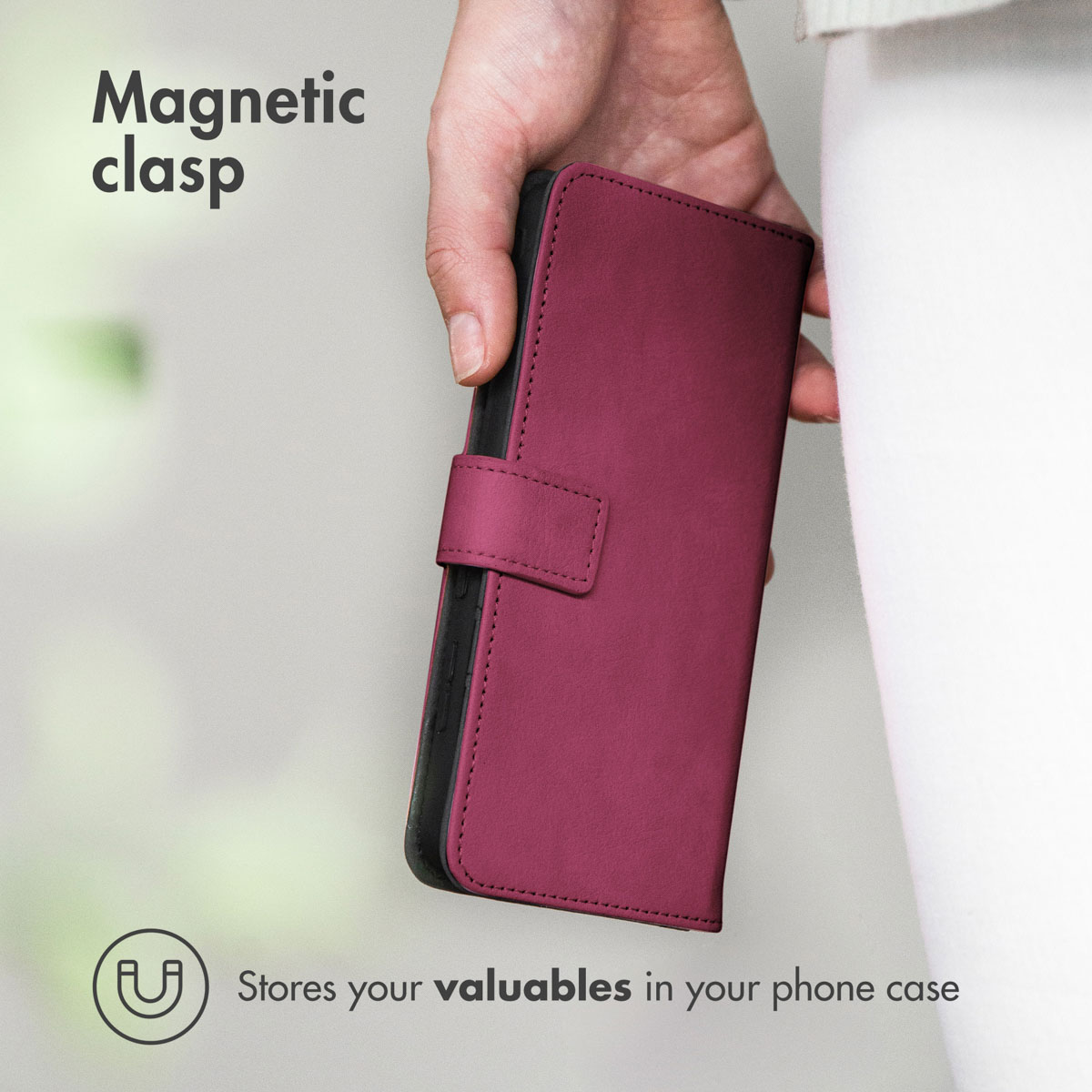 Une main tient un étui de téléphone en cuir magenta fermé avec un fermoir magnétique.