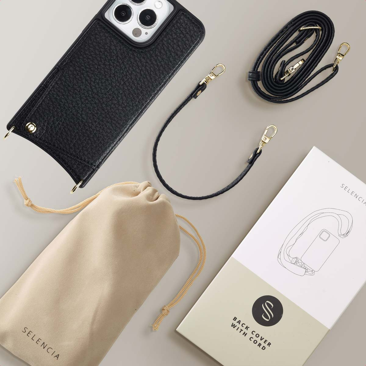 Funda de teléfono negra con correas, bolsa y caja sobre fondo gris.