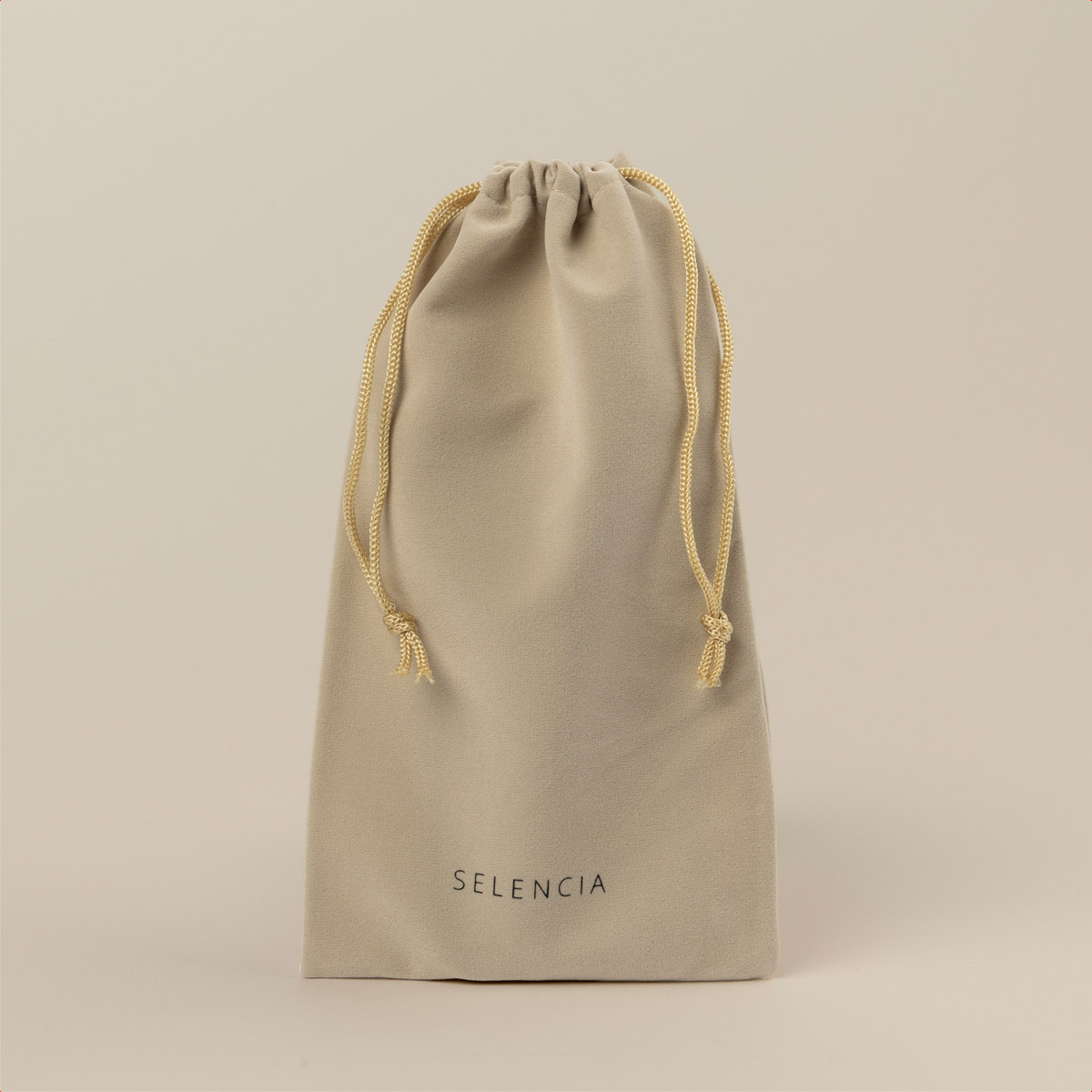 Un sacchetto di velluto beige con coulisse dorate e il marchio SELENCIA è su sfondo neutro.