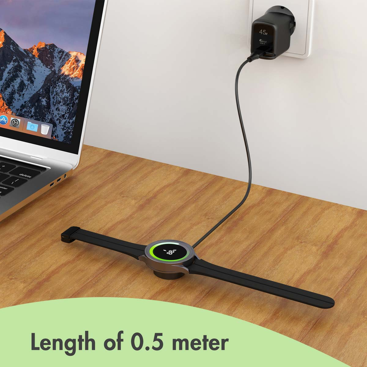 A black smartwatch charges on a wooden desk, connected by a cable to a wall outlet. A laptop sits nearby.