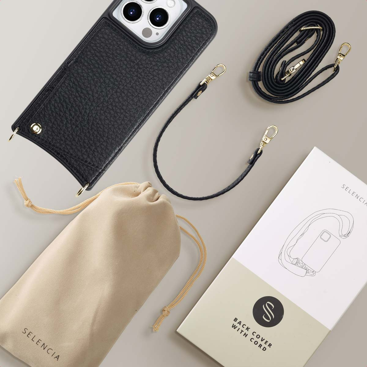 Funda de teléfono de cuero negro con correas, bolsa y caja de producto sobre fondo claro.