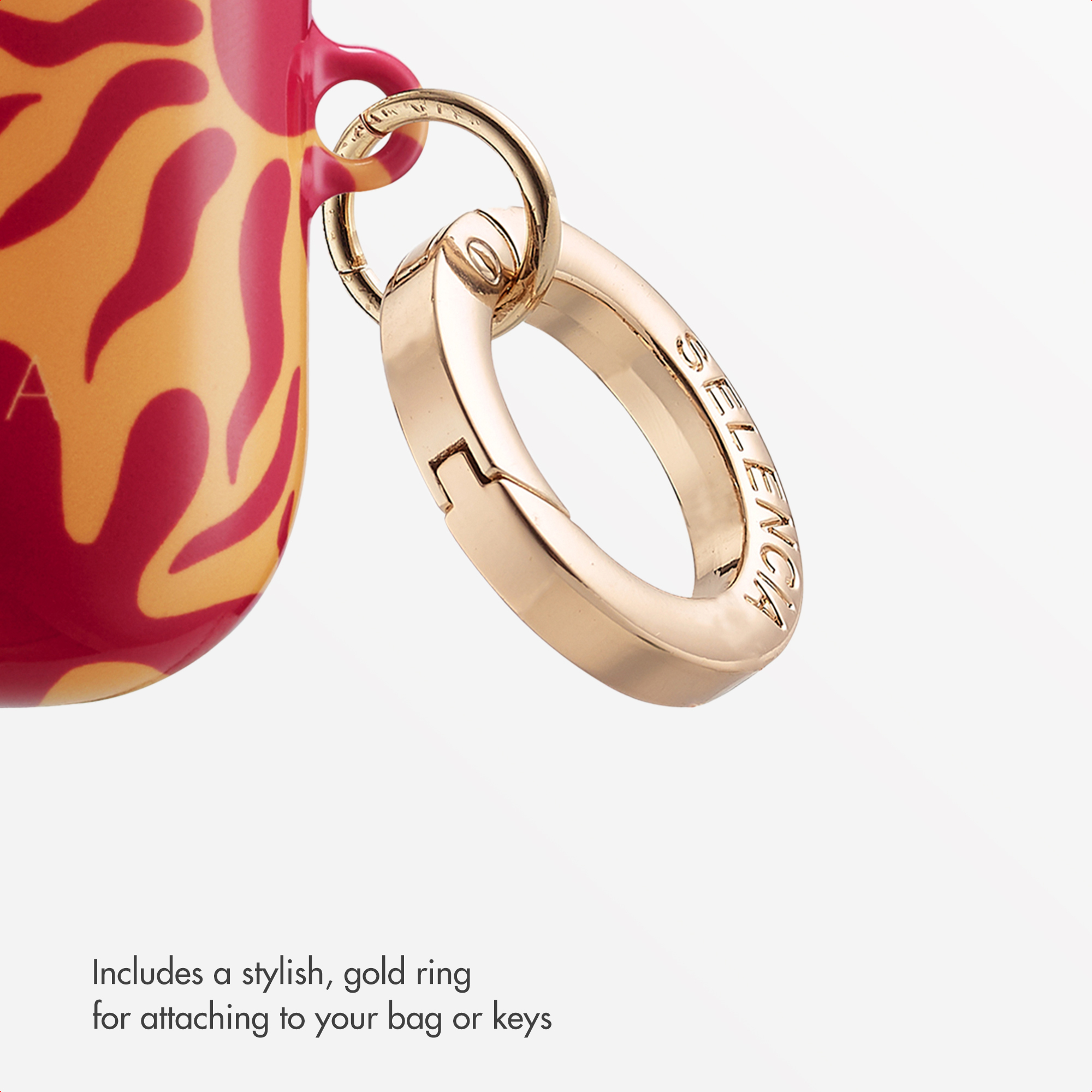 Primer plano de un elegante anillo dorado unido a una funda con patrón rojo y amarillo sobre fondo blanco.