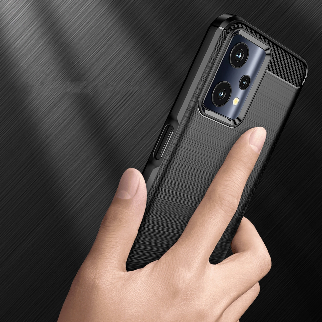Una mano tiene uno smartphone nero con custodia protettiva testurizzata su sfondo scuro.