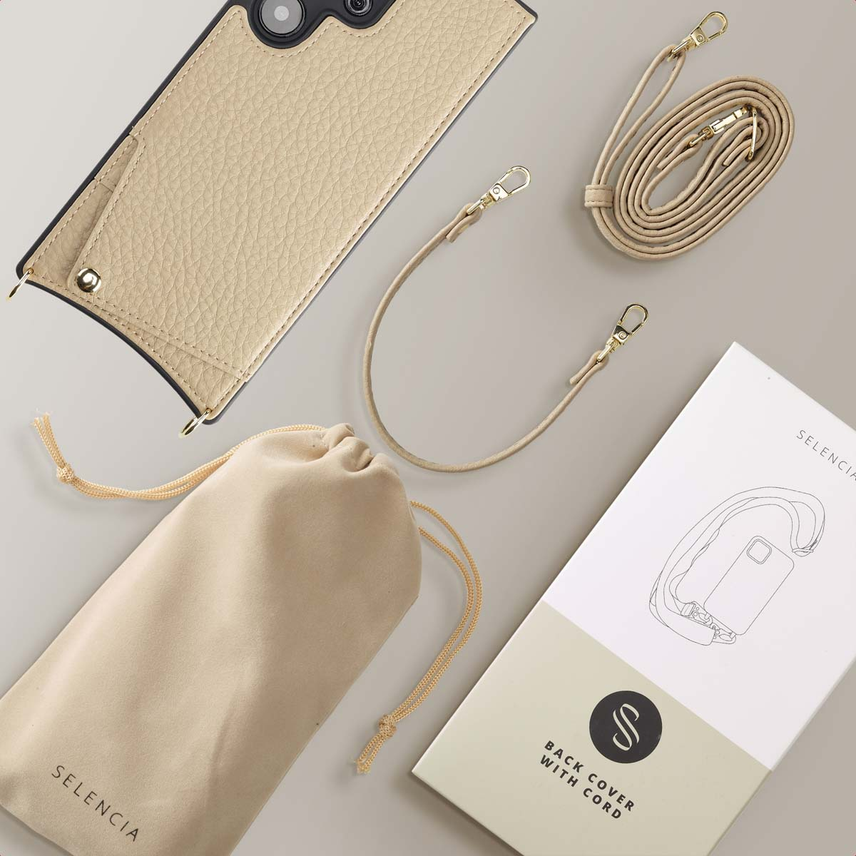Funda de móvil beige con correa, bolsa y caja sobre fondo gris.