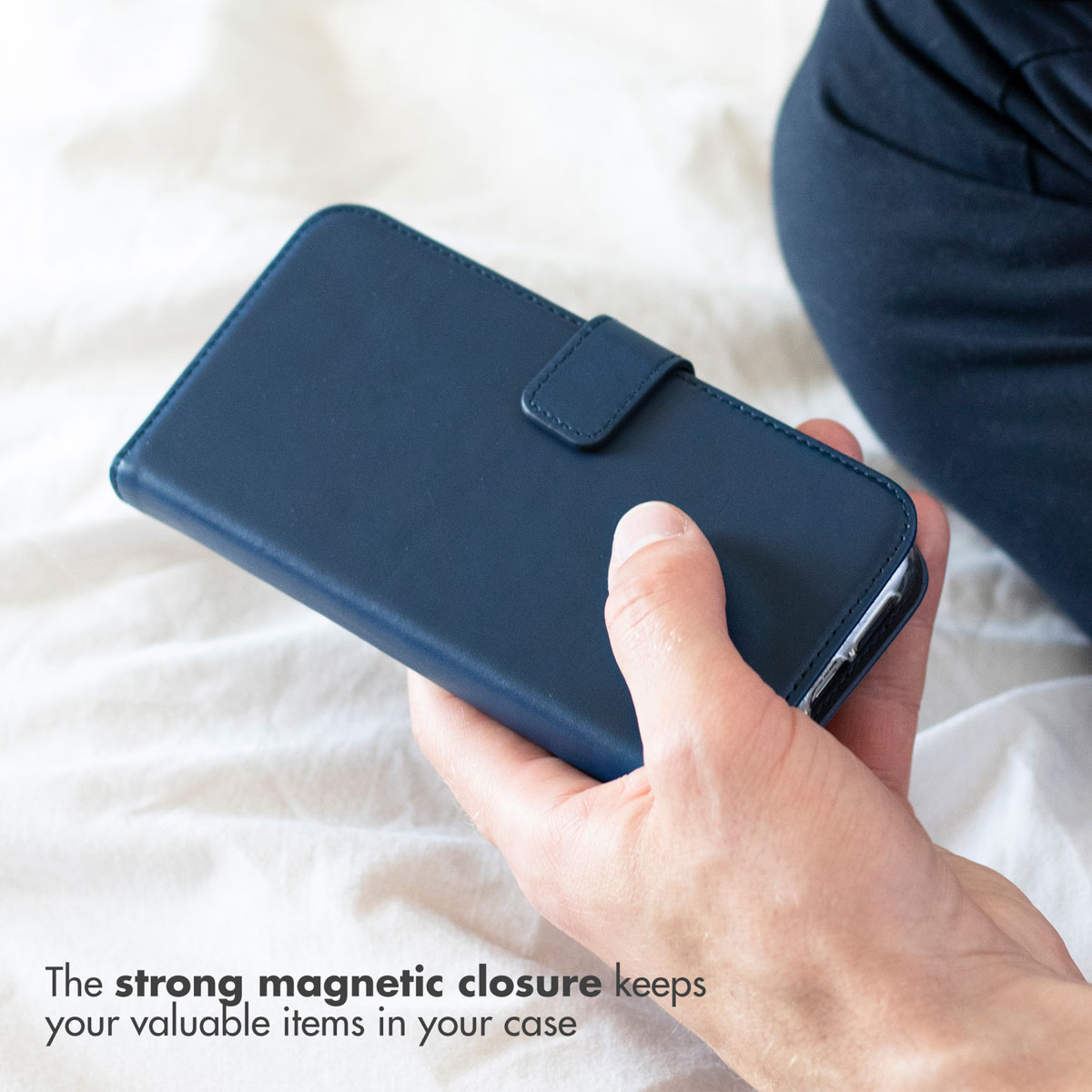 Une main tient un étui de téléphone bleu foncé fermé avec fermeture magnétique.