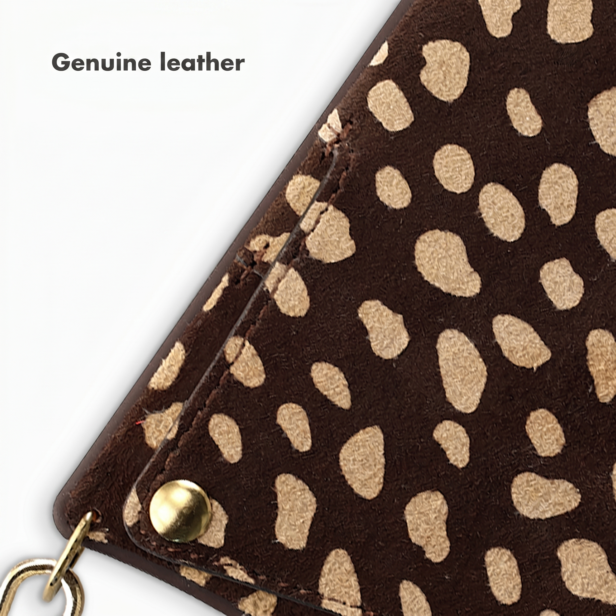 Nahaufnahme von braunem Leder mit beigen Flecken, goldenem Knopf und Ring auf weißem Hintergrund.