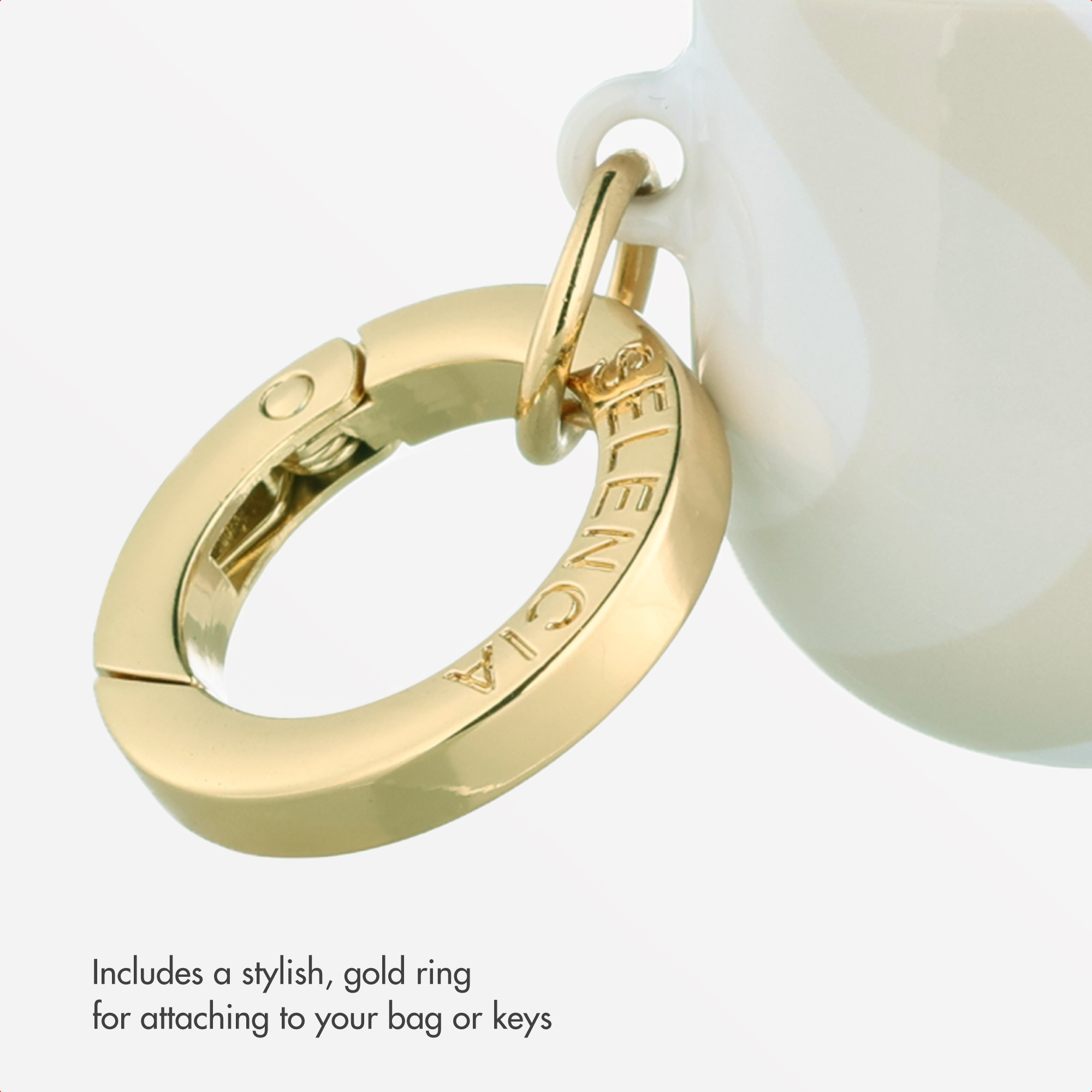 Un anillo dorado con grabado cuelga de un recipiente blanco sobre fondo blanco.