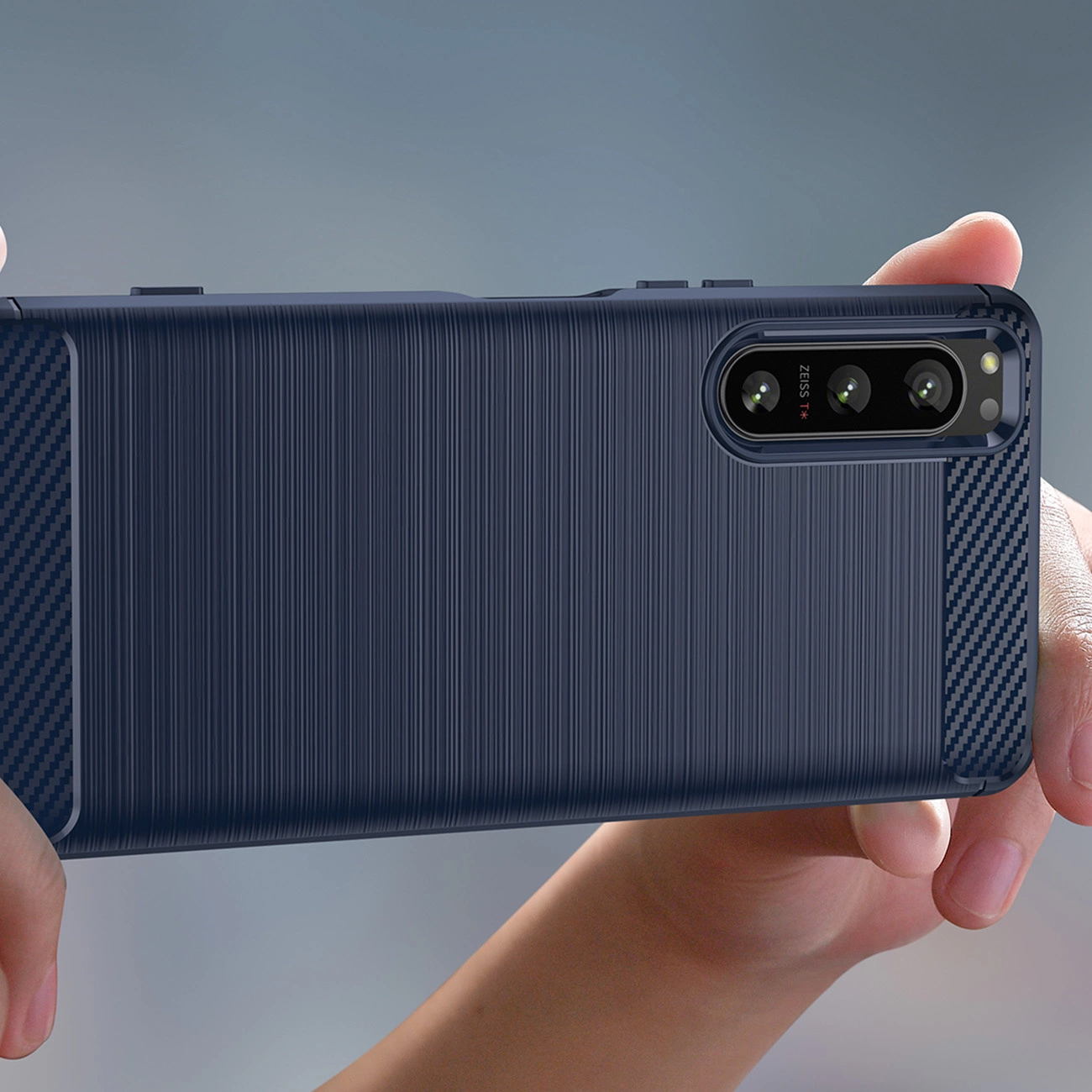 Custodia per smartphone blu con texture spazzolata e dettagli in carbonio tenuta in mano.