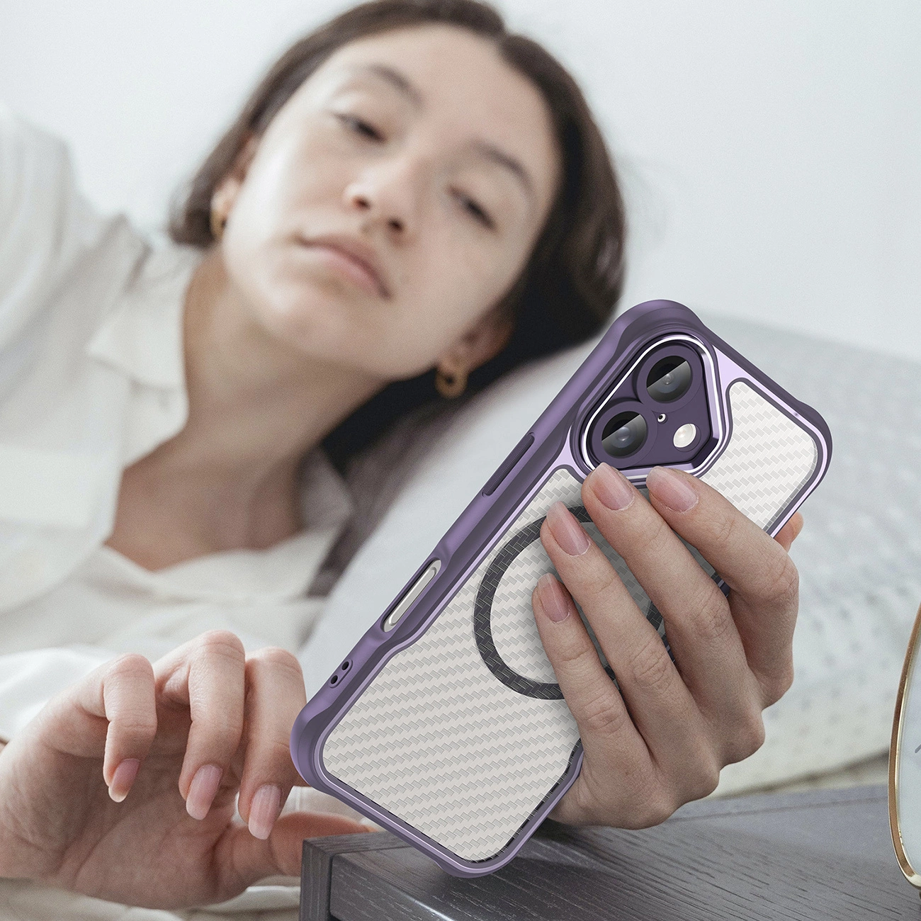Una donna in abiti bianchi tiene in mano uno smartphone viola con una parte posteriore fantasia.