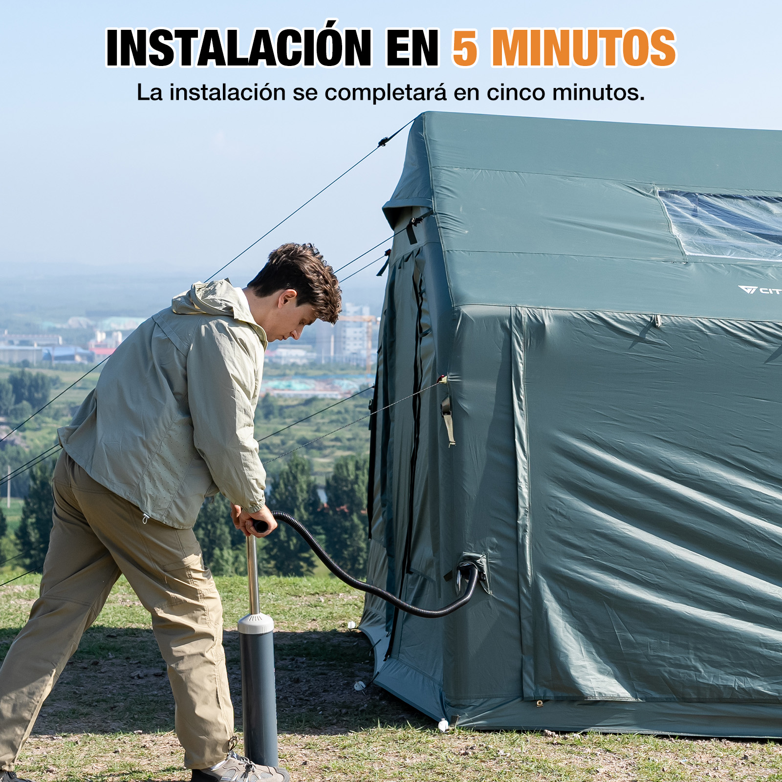 Un hombre infla una gran tienda de campaña verde al aire libre con una bomba manual.