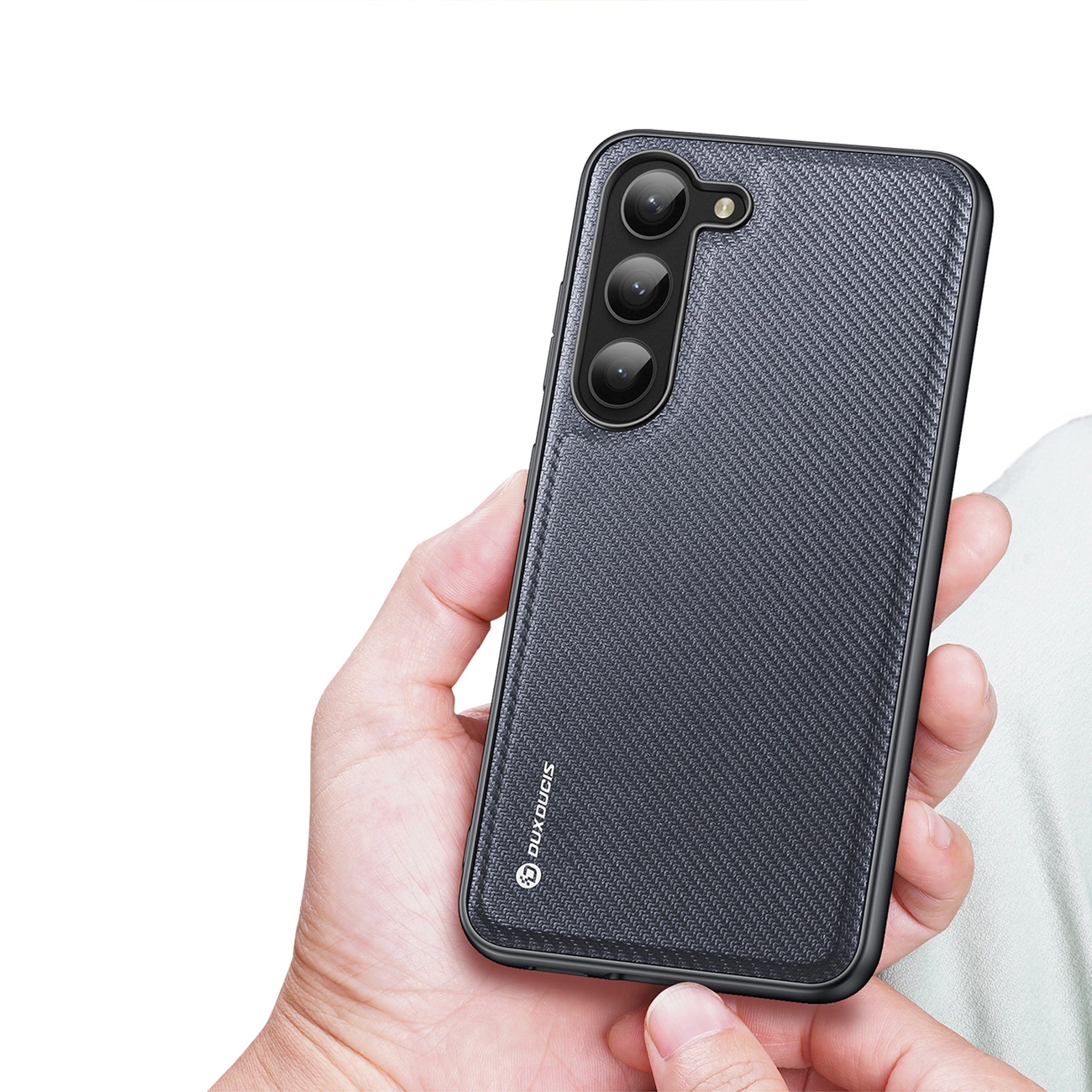 Una mano tiene uno smartphone scuro con cover testurizzata e tre fotocamere verticali.